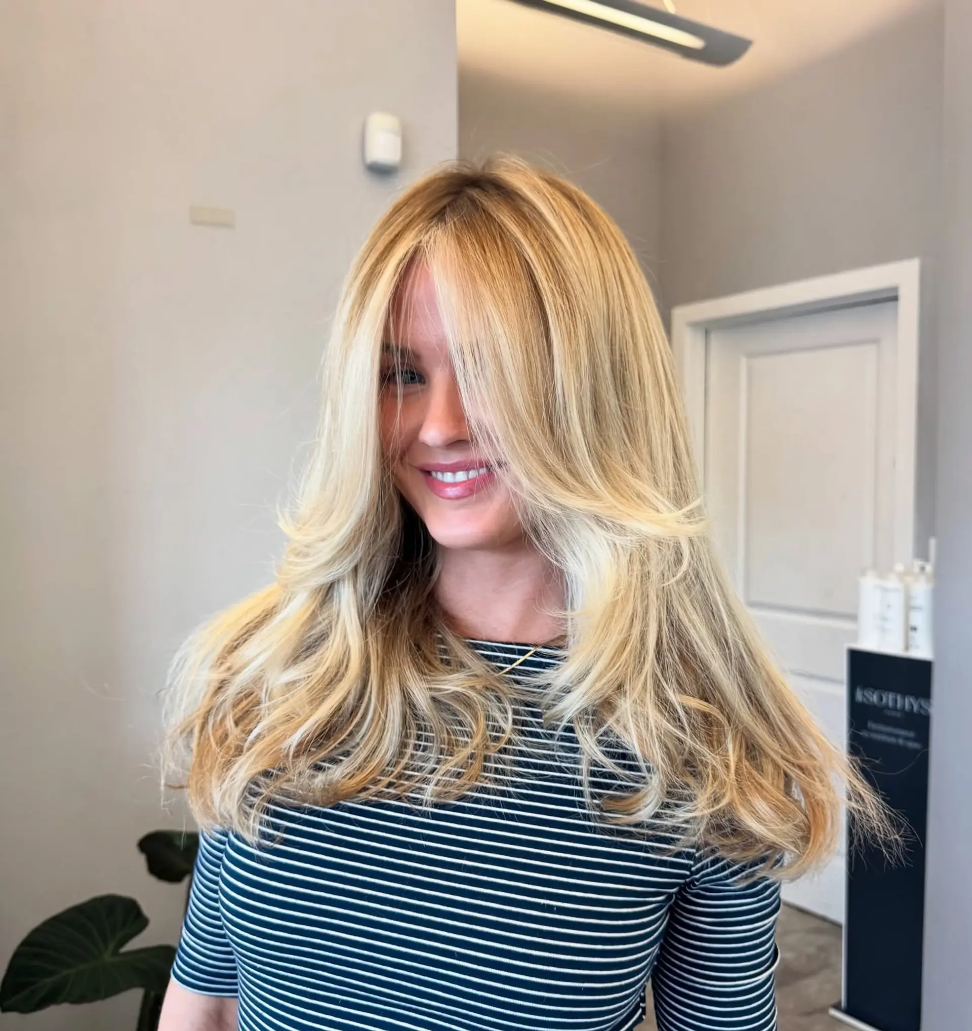 A long, layered haircut with face-framing layers and curtain bangs. The hair is styled with a soft wave. 1