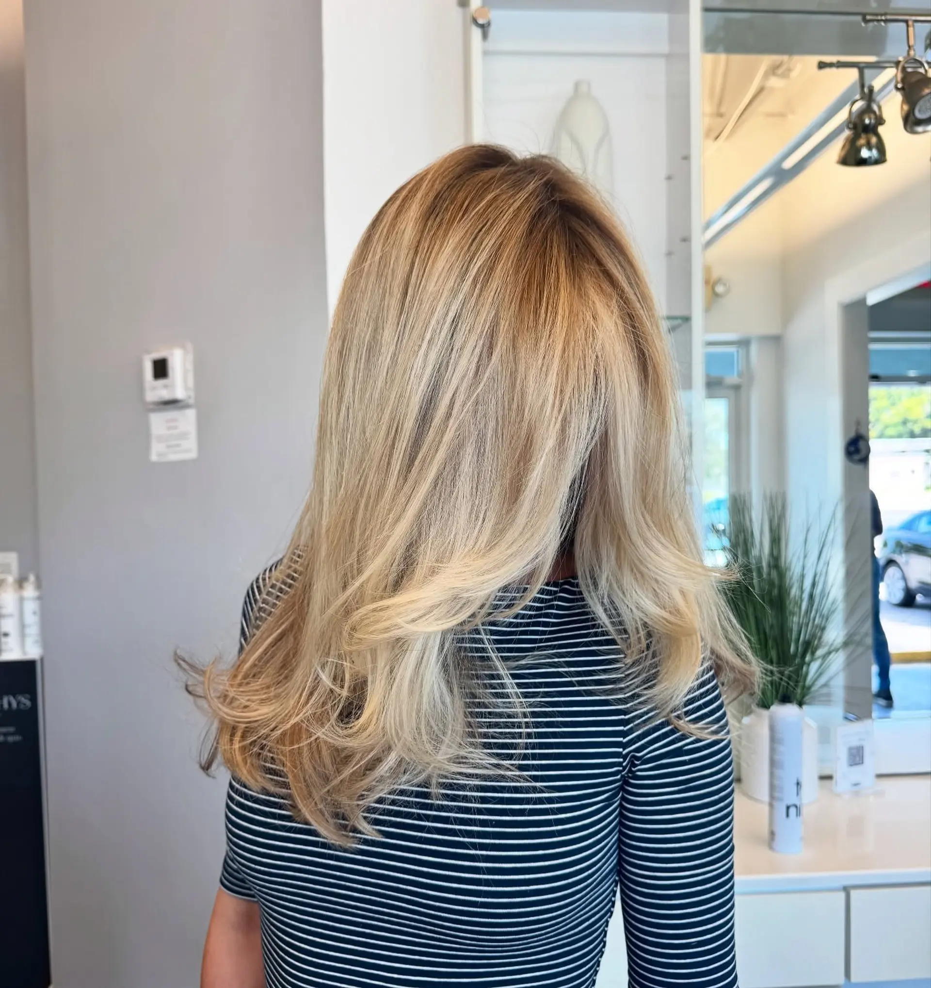 A long, layered haircut with face-framing layers and curtain bangs. The hair is styled with a soft wave. 2