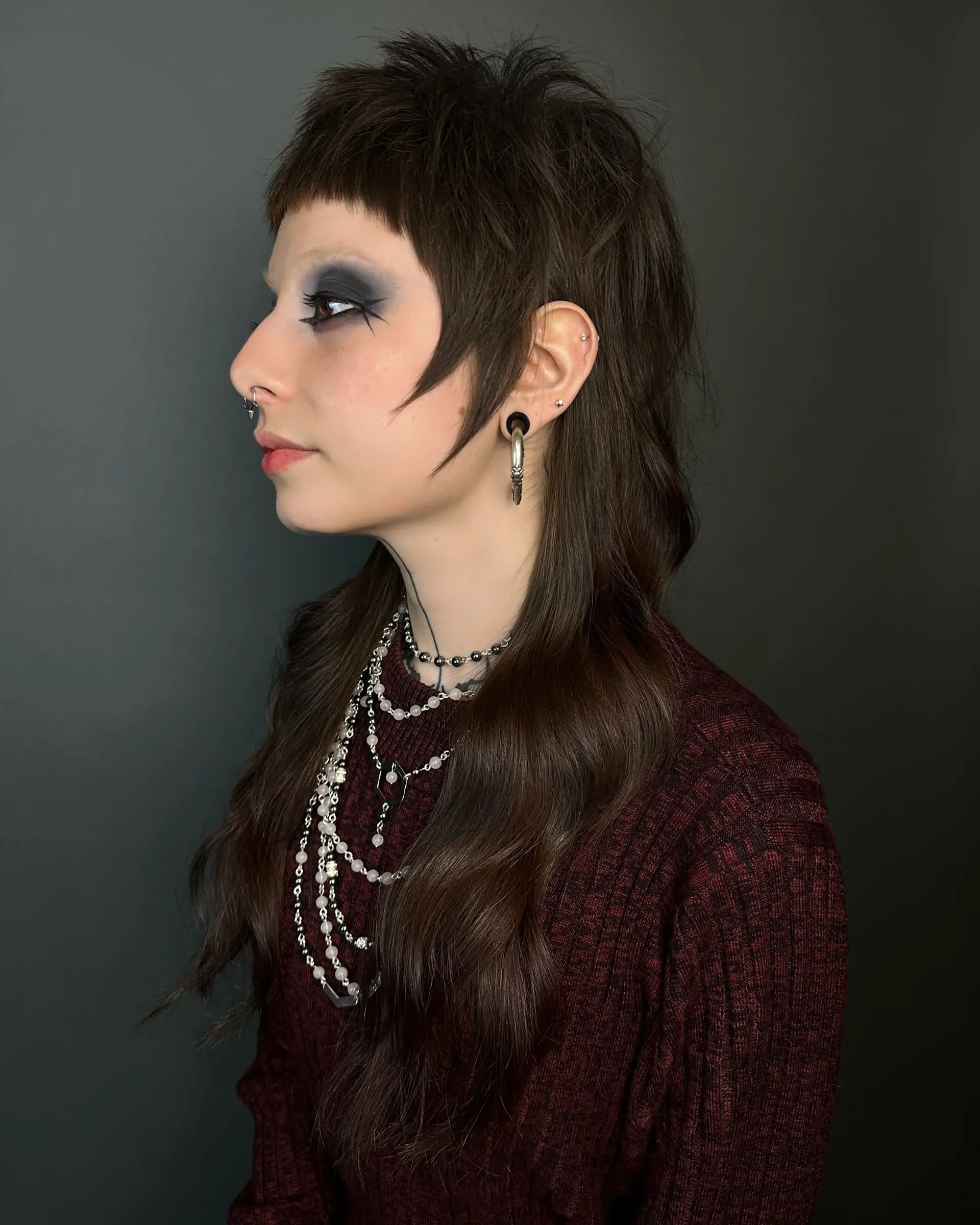 A textured razor-cut shag mullet featuring blunt micro bangs, piecey face-framing layers, and long lengths flowing down the back. 1