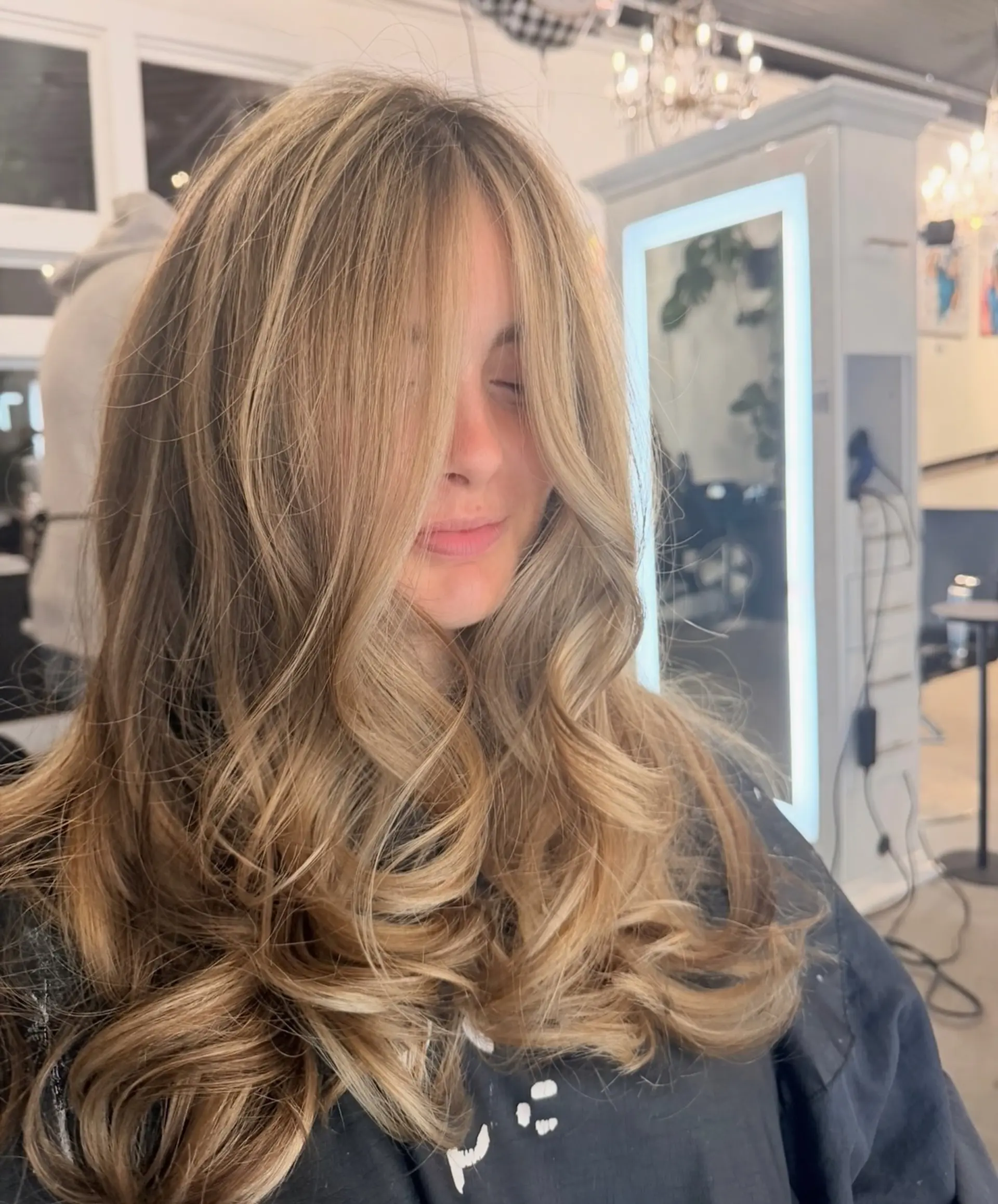 A voluminous blowout styled with soft, cascading curls and face-framing curtain layers. 1