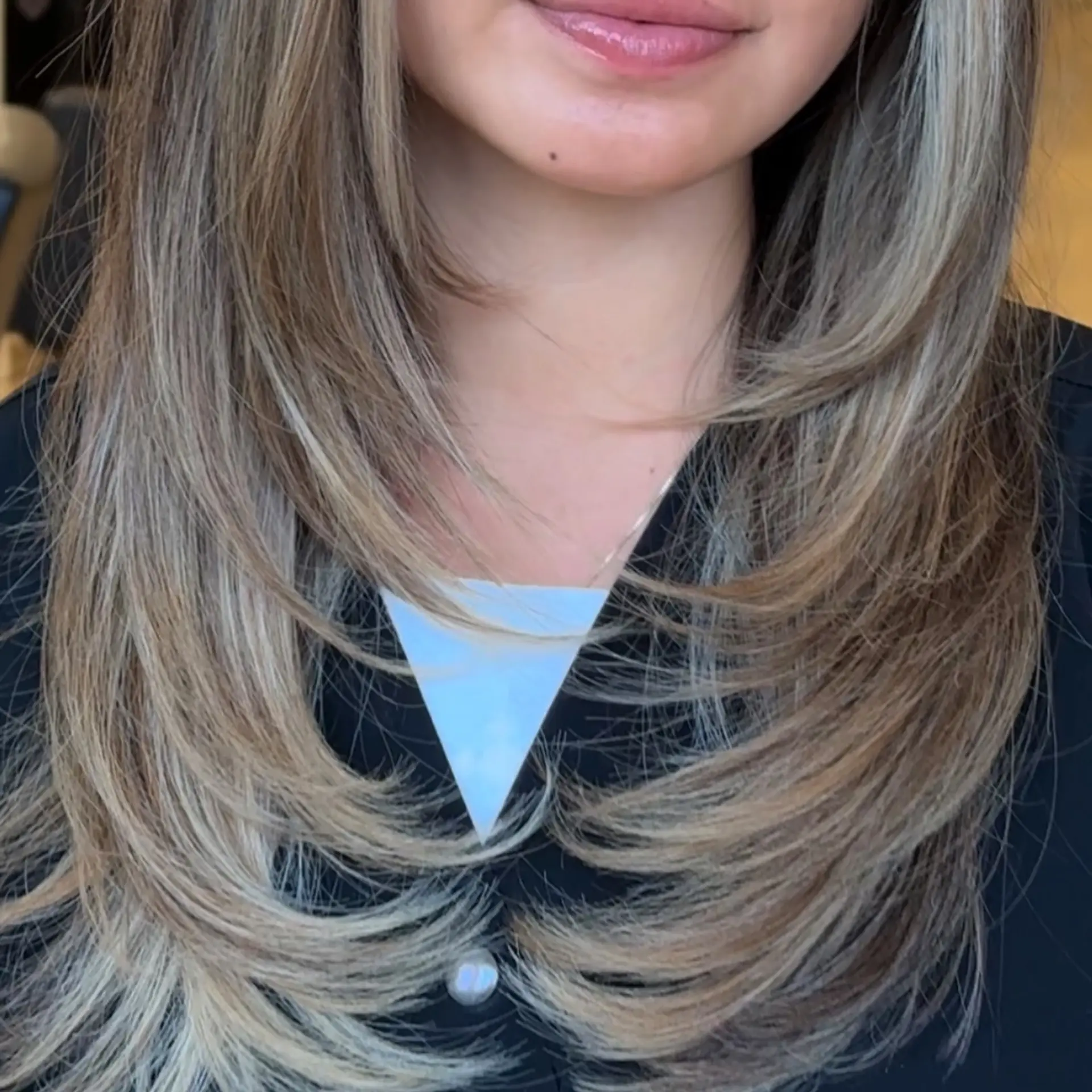 Long dimensional bronde hair styled into bouncy, face-framing layers with smooth curved ends. 1