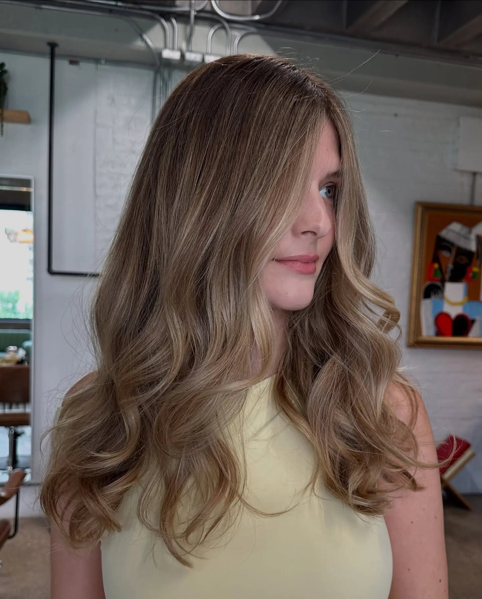 Long bronde hair with beachy waves achieved through a balayage technique. 4
