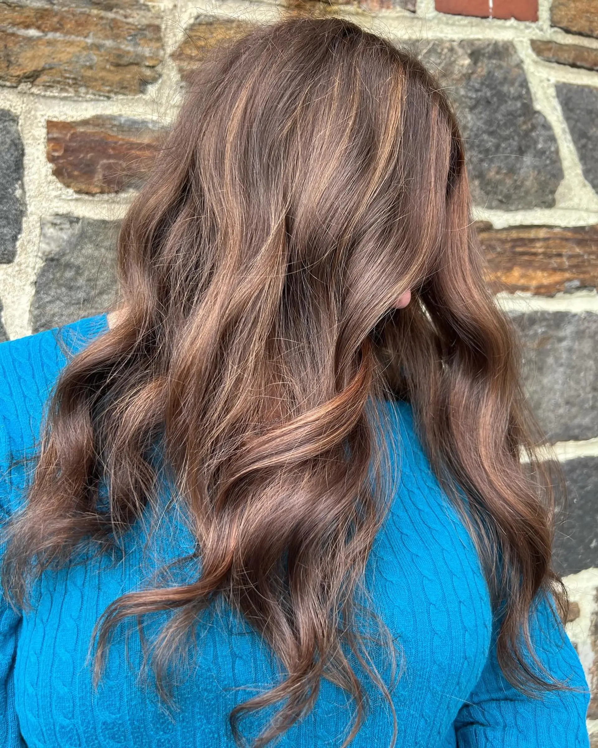 Rich chocolate brown hair styled into relaxed, effortless waves with subtle warm caramel highlights. 1