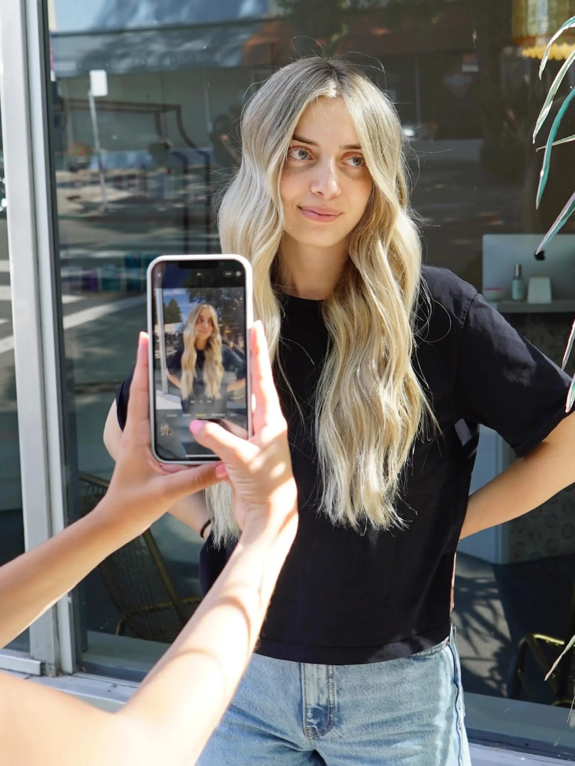 Long lived-in blonde hair styled with a center part and soft, effortless beach waves. 1
