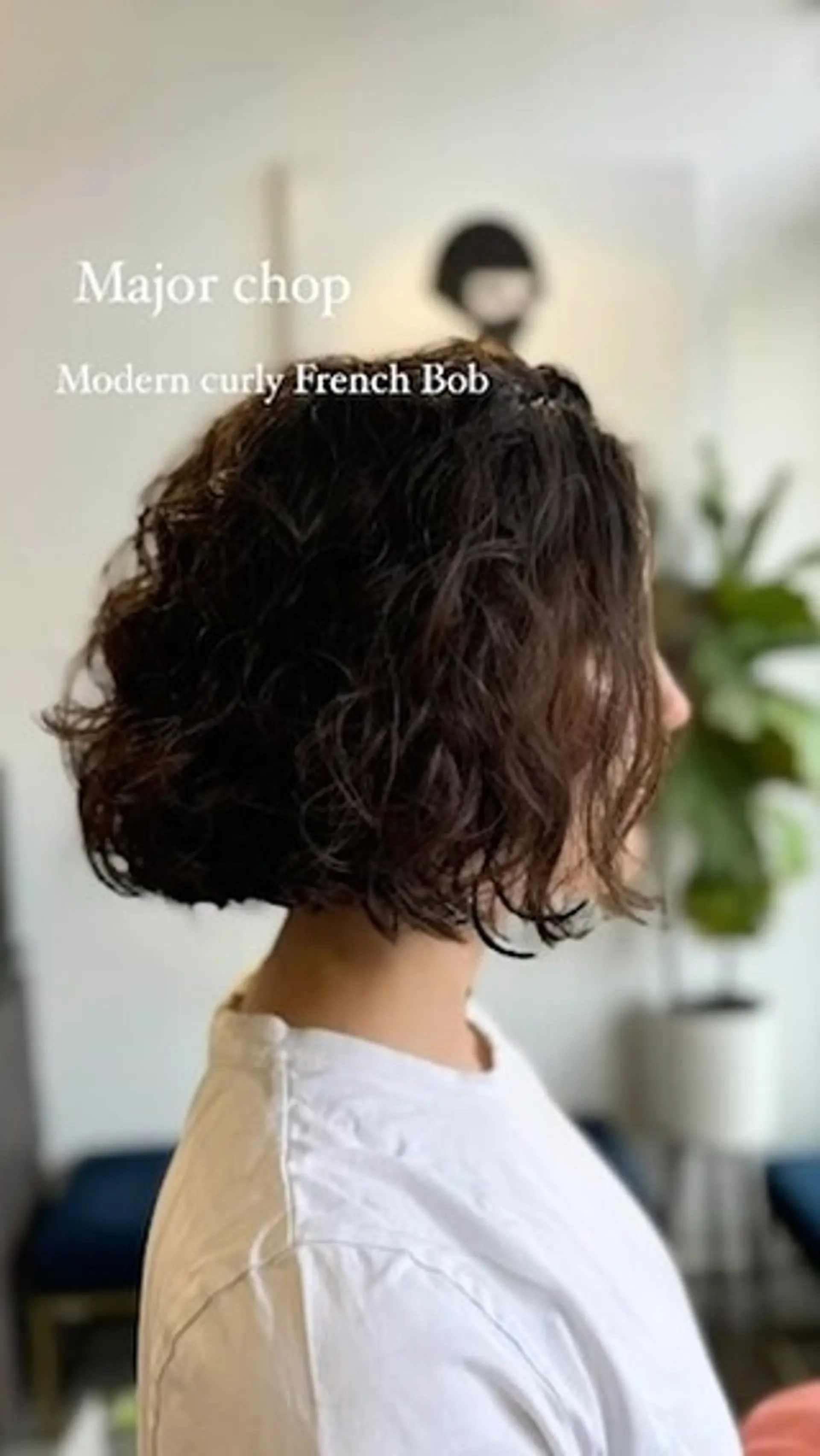 A textured curly French bob cut to chin length with defined natural waves and soft volume. 1