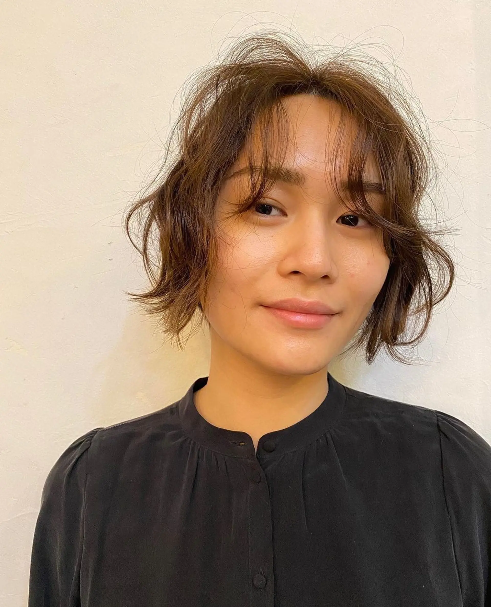 The Messy Chic Bob features a short, wavy cut with a side-swept fringe and a slightly tousled texture, creating a casual and elegant look with natural brown hues. (Hair by Coco) 1