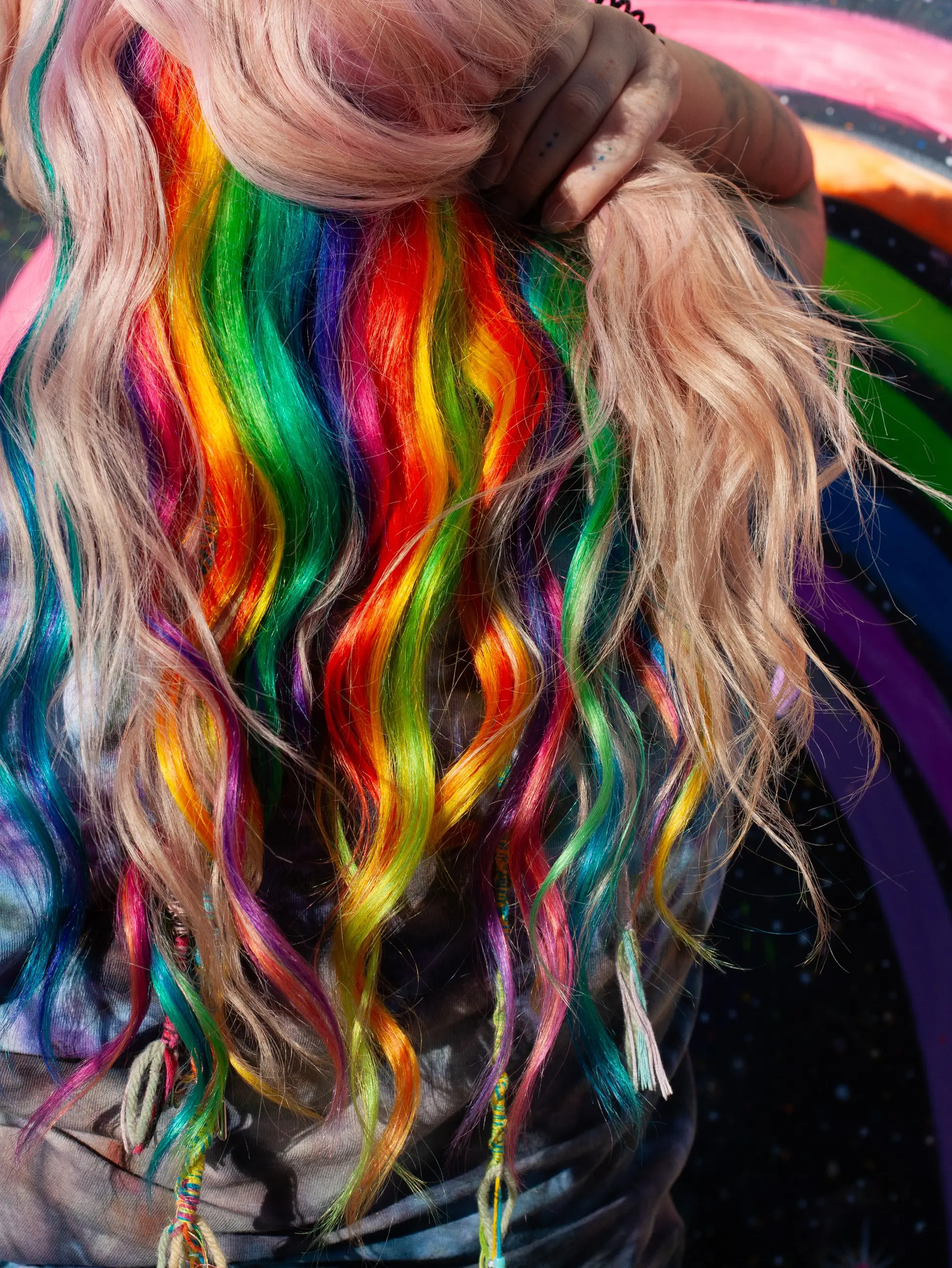 Hidden rainbow underlayer beneath pale platinum blonde hair, styled with textured loose waves. 1