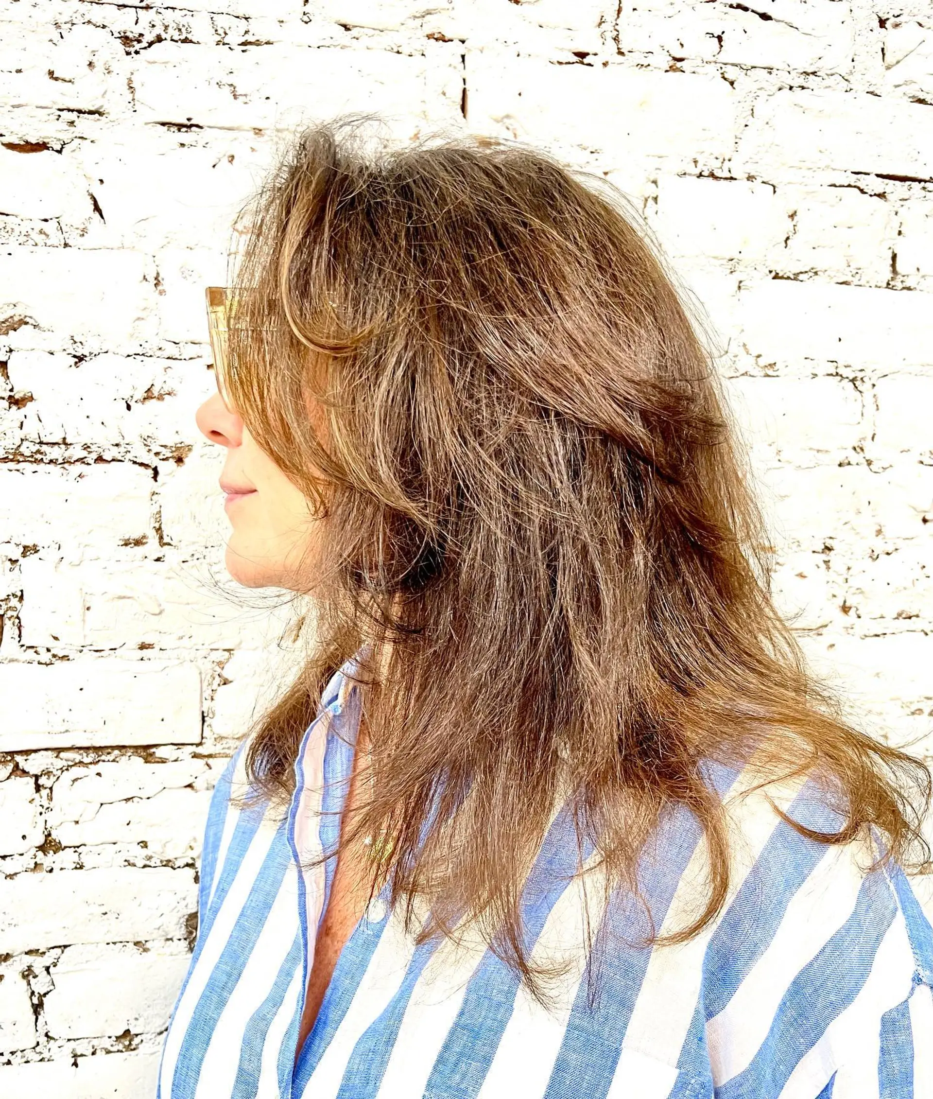 A medium-length textured shag haircut featuring feathered layers and soft, face-framing curtain bangs in a natural warm brown shade. 1