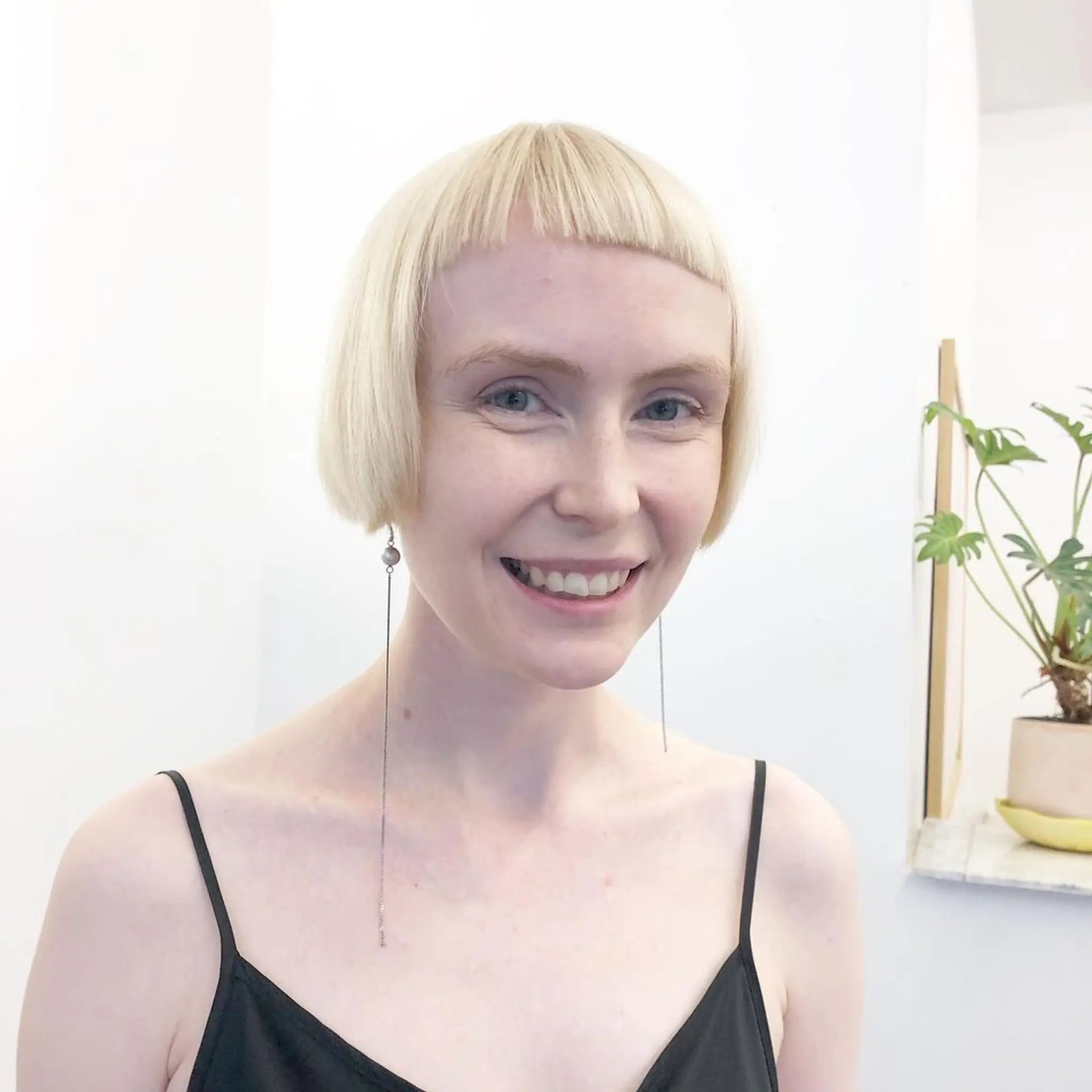 A chic, short hairstyle with a straight texture and a modern cropped bob cut. Blunt cut bangs rest just above the eyebrows, paired with a striking platinum blonde color for a fresh, edgy look by Takeo.