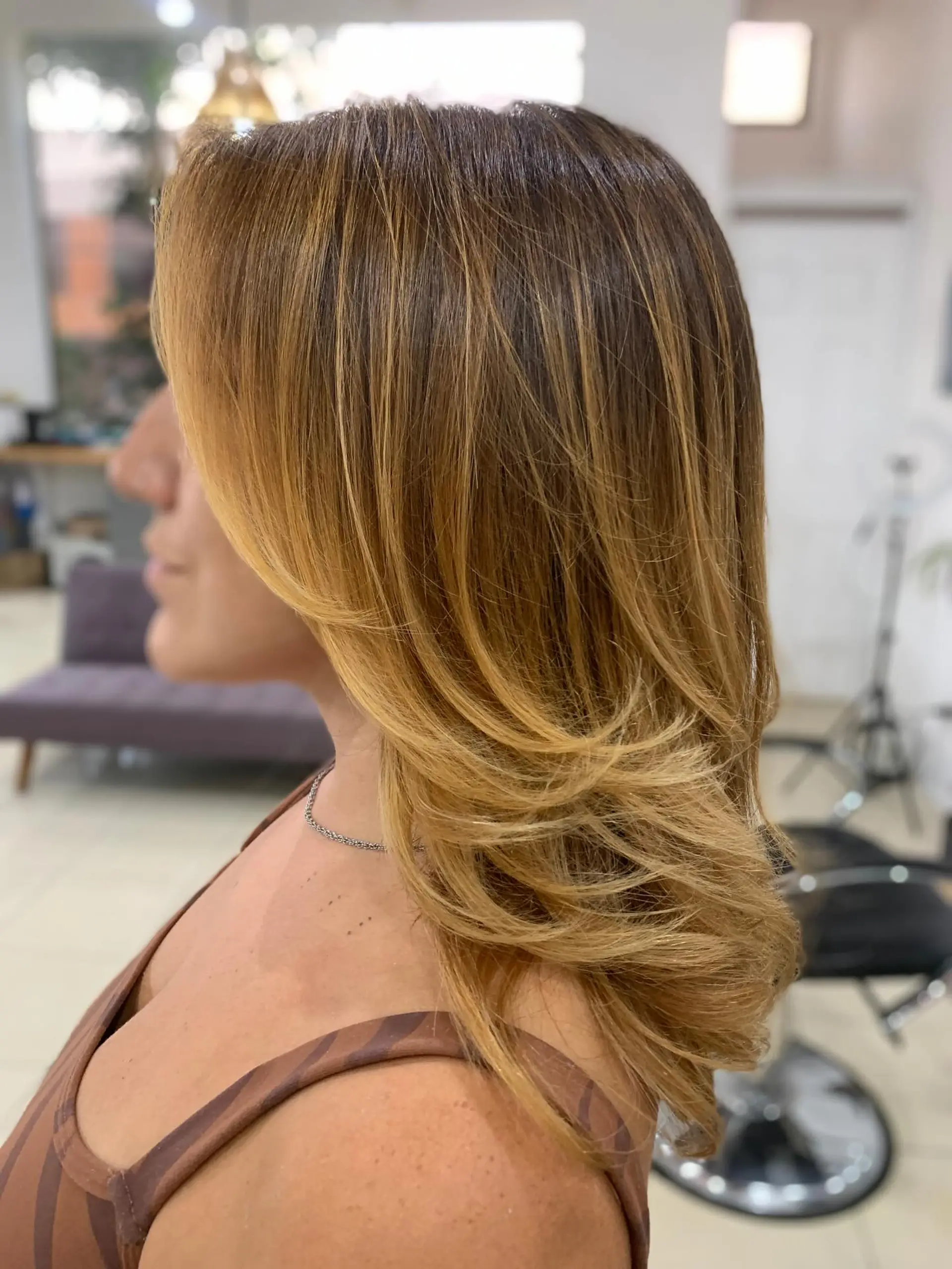 A medium-length layered hairstyle with a soft blowout, face-framing layers, and honey blonde highlights. 1