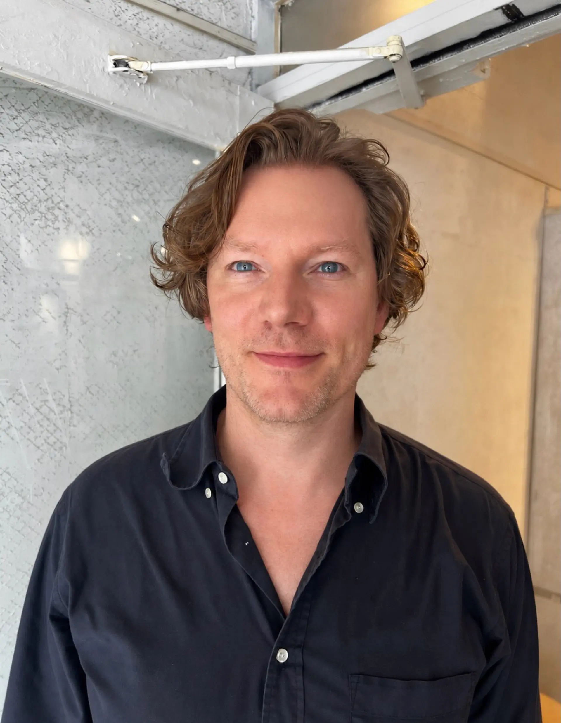 A men's short cut featuring soft, natural waves with light volume, swept gently away from the forehead. 1