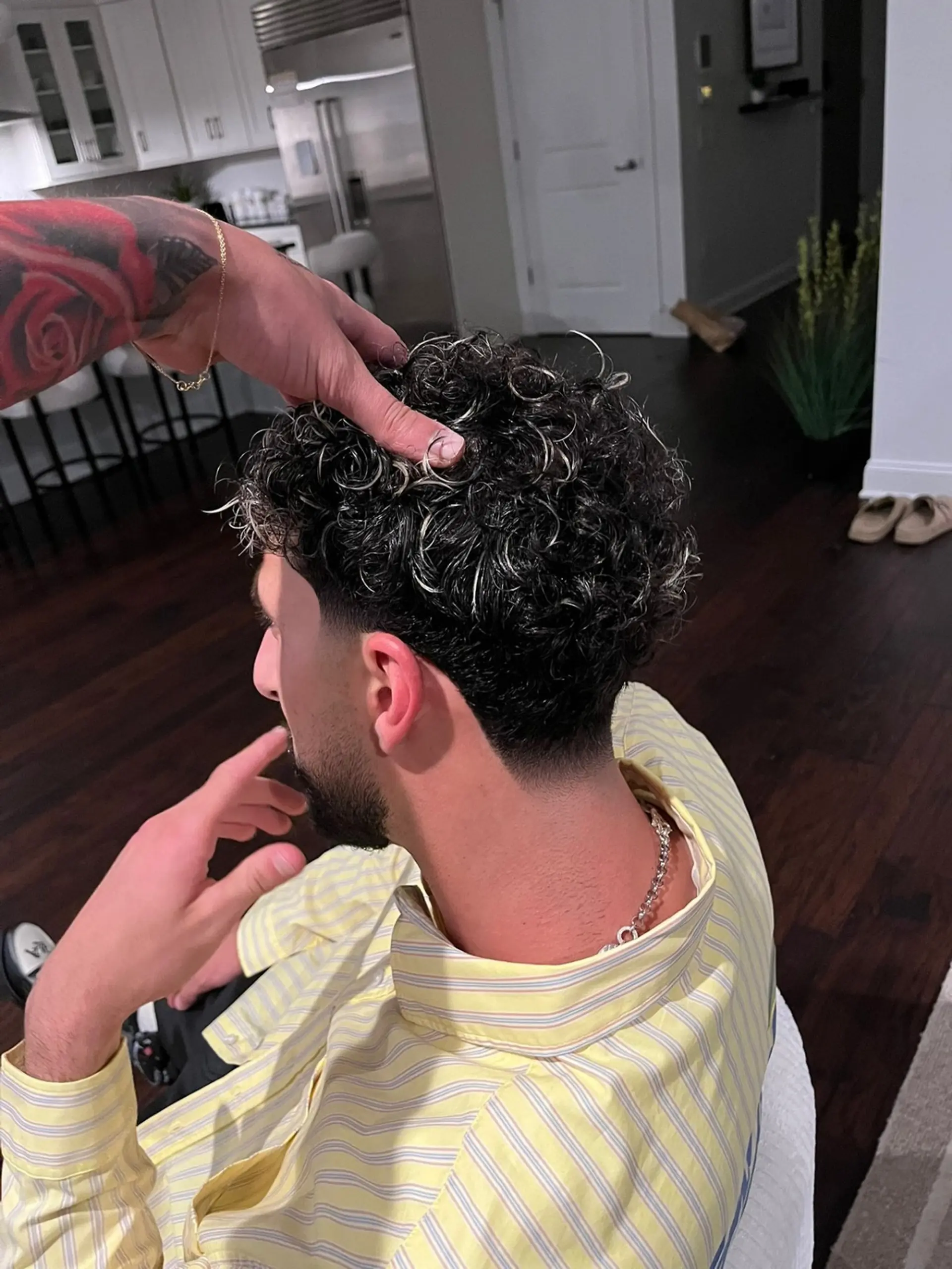 A men's low taper fade with defined curls on top accented by frosted blonde tips. 1