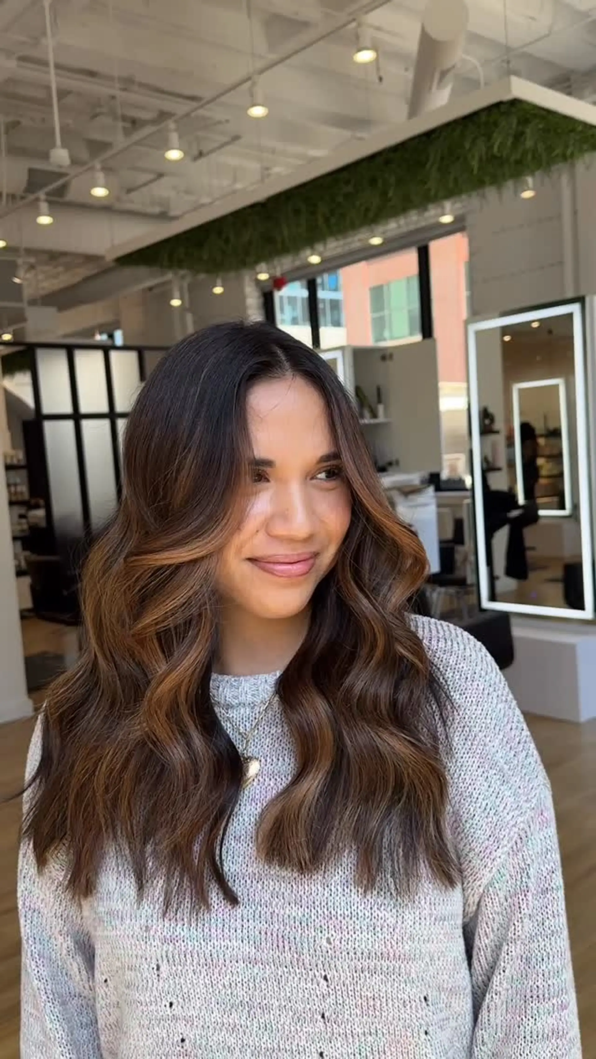 Long dark brunette hair styled with soft loose waves and warm caramel face-framing balayage highlights. 1