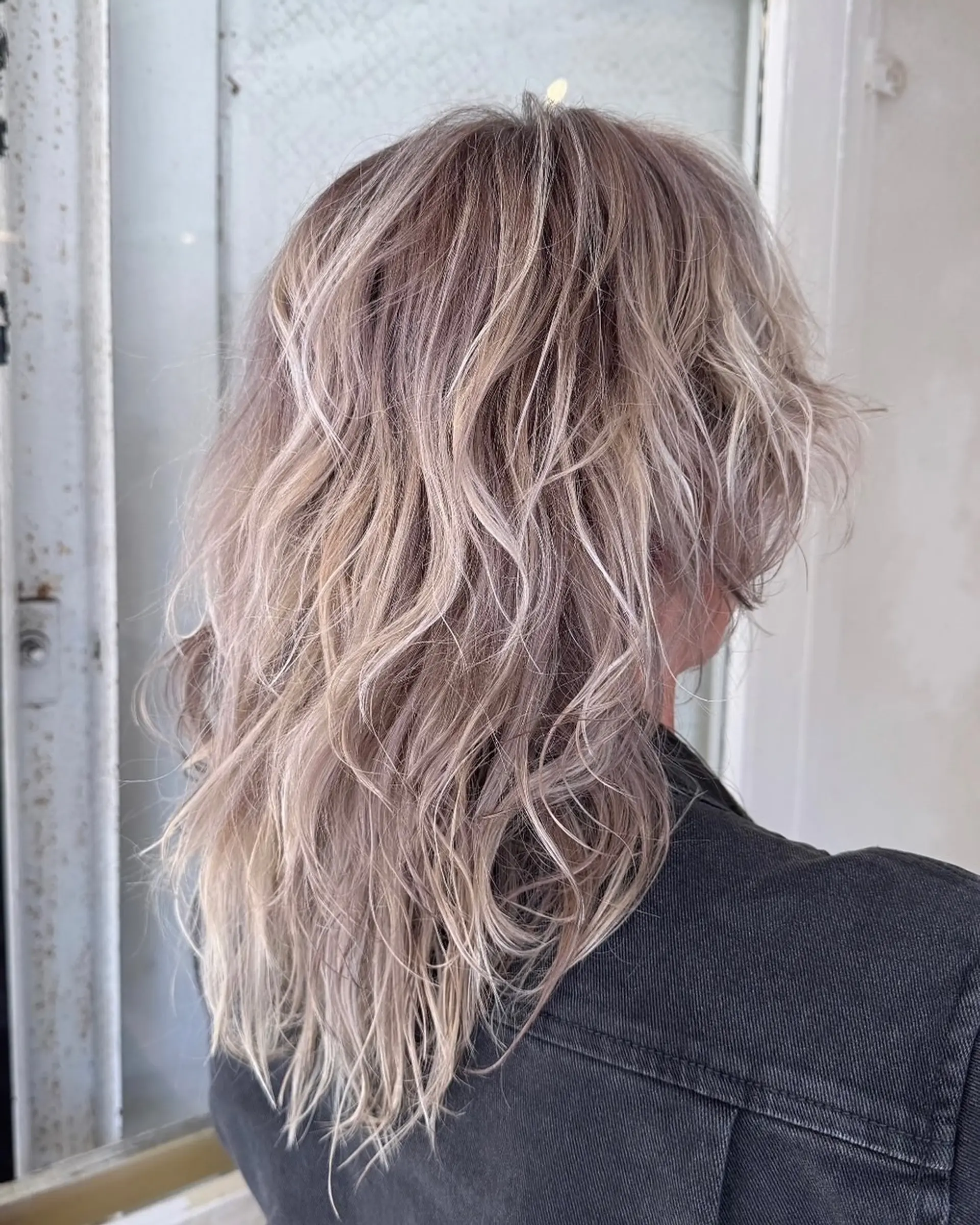 Medium-length wavy hair with silver and ash blonde tones, textured layers, and natural waves. 1