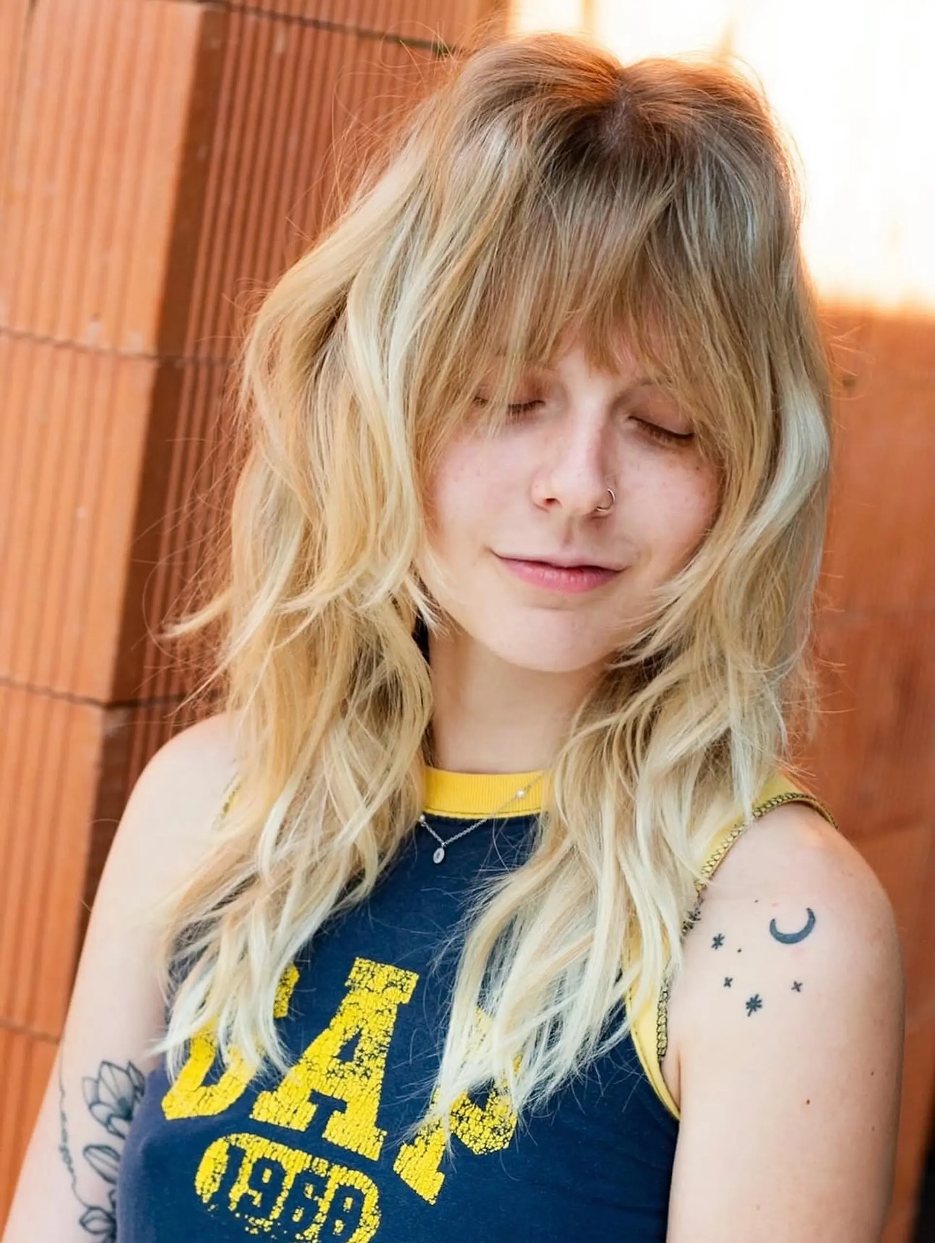 A textured blonde shag haircut featuring feathered face-framing layers and full, wispy bangs. 1