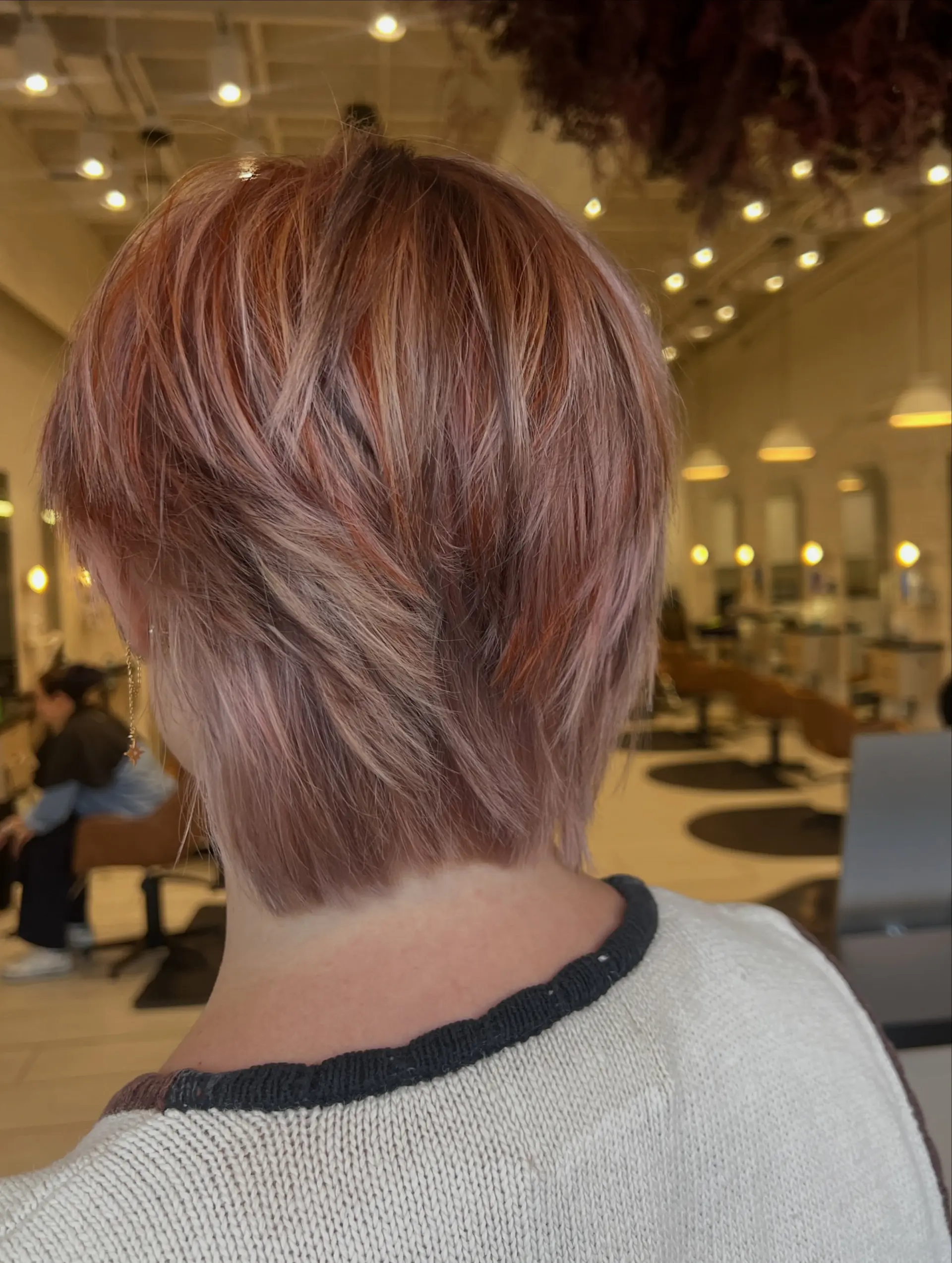 A textured short bixie cut featuring dimensional calico coloring with blended tones of copper, rose gold, and blonde. 1