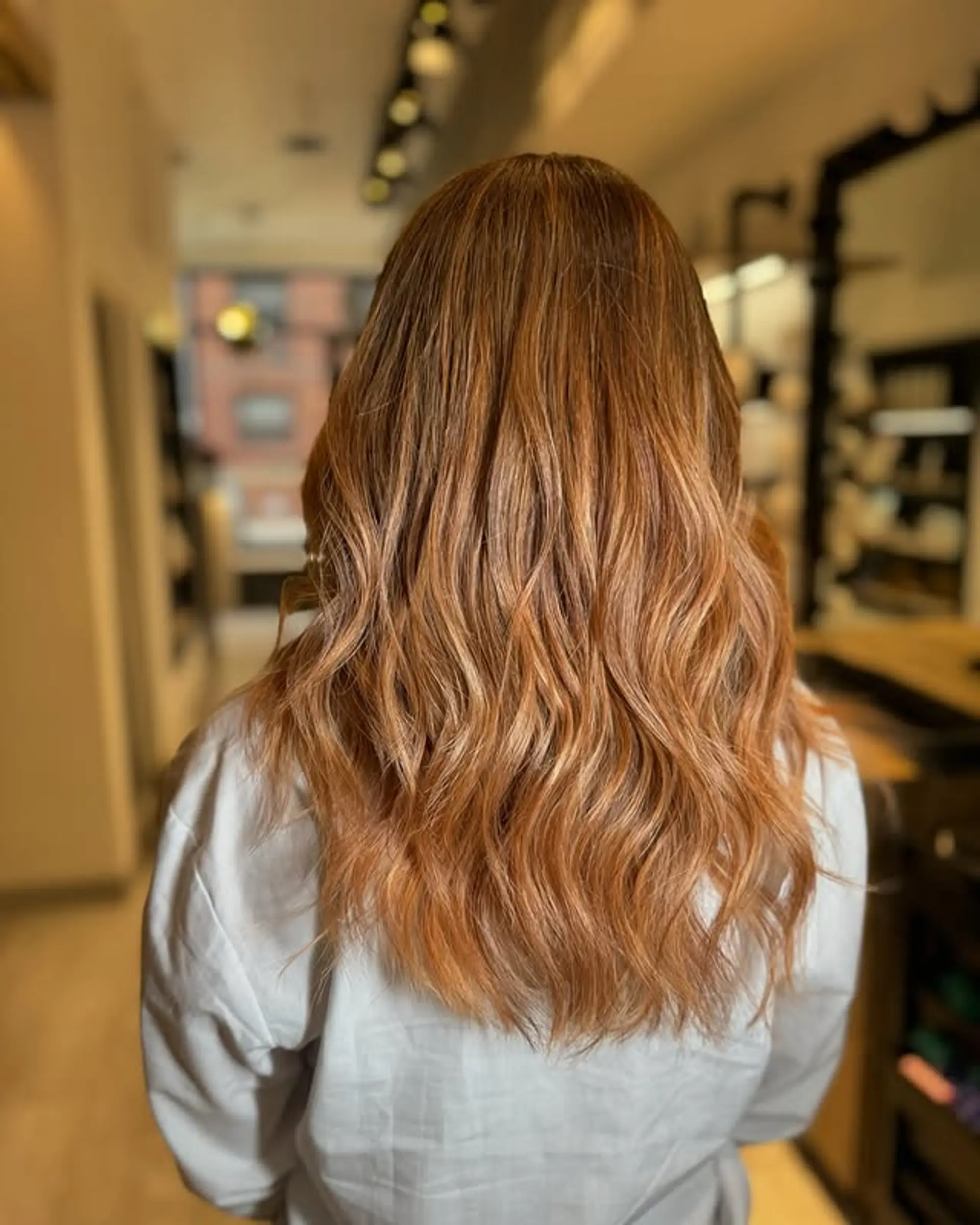 A stunning balayage that blends copper and blonde tones seamlessly, creating a beautiful, wavy hairstyle. 1