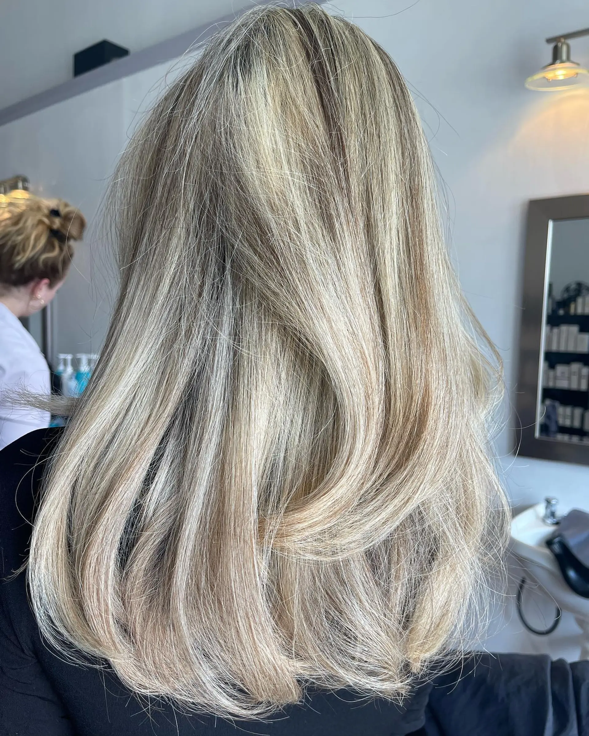 Long dimensional blonde hair cut with butterfly layers and styled in a soft, voluminous blowout. 1
