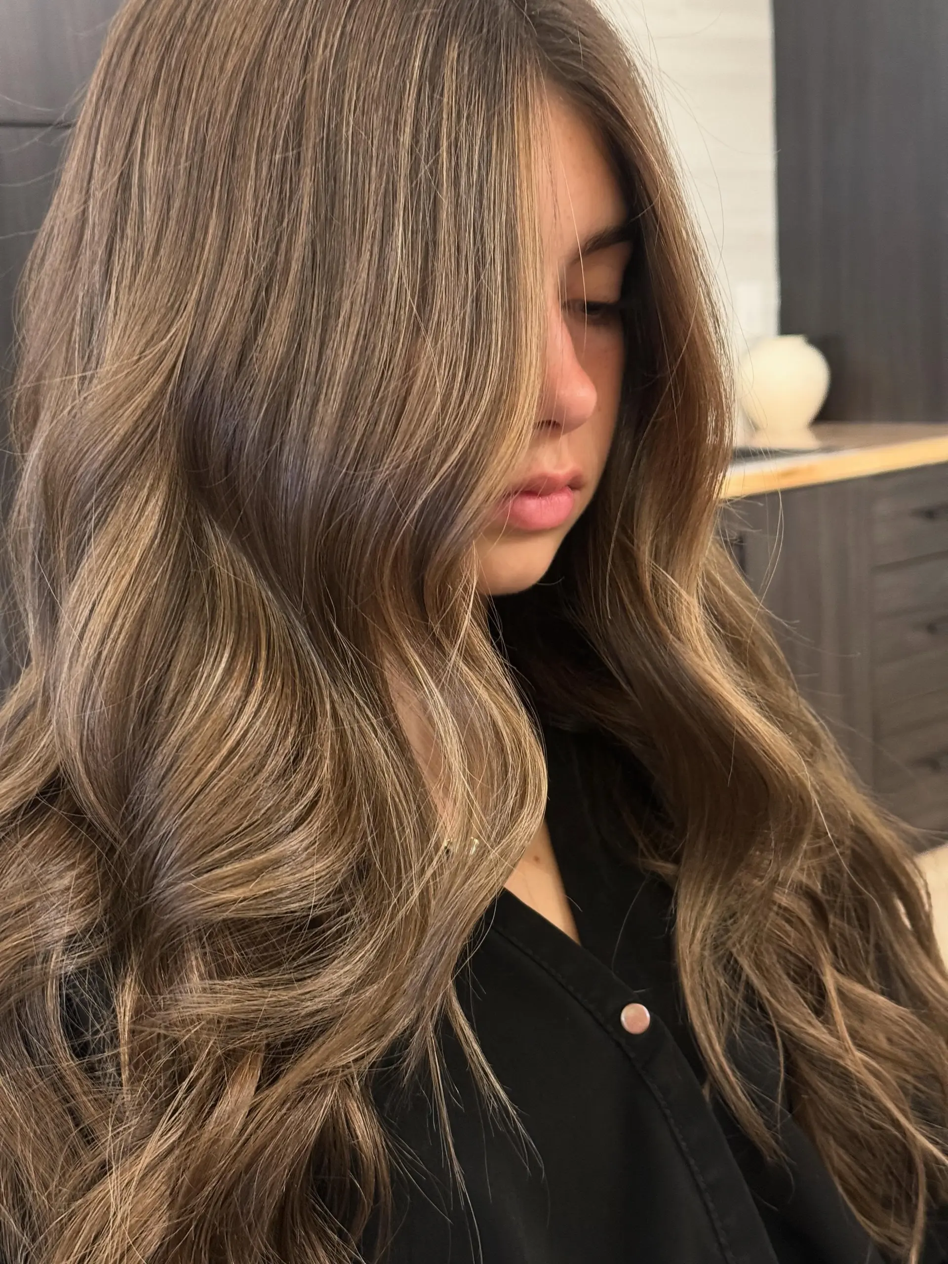 Long, flowing dimensional brunette hair with seamless ash blonde highlights styled into soft, polished blowout waves. 1