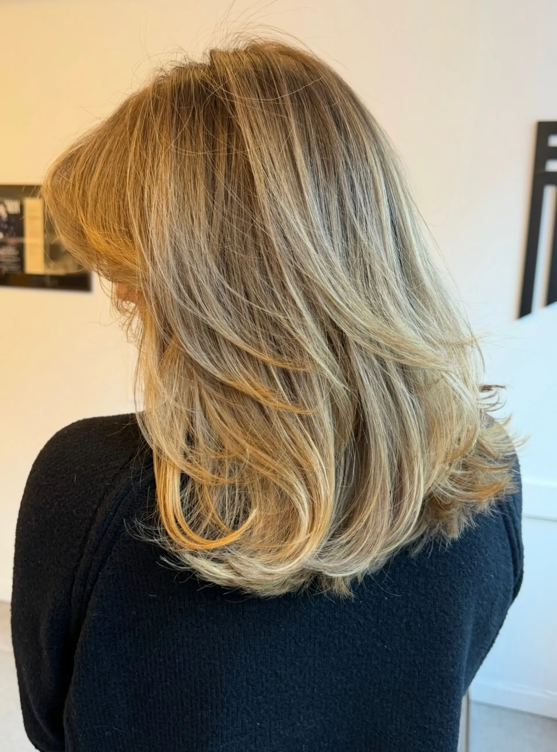 A medium-length layered haircut with soft face-framing layers and dimensional blonde highlights. 1