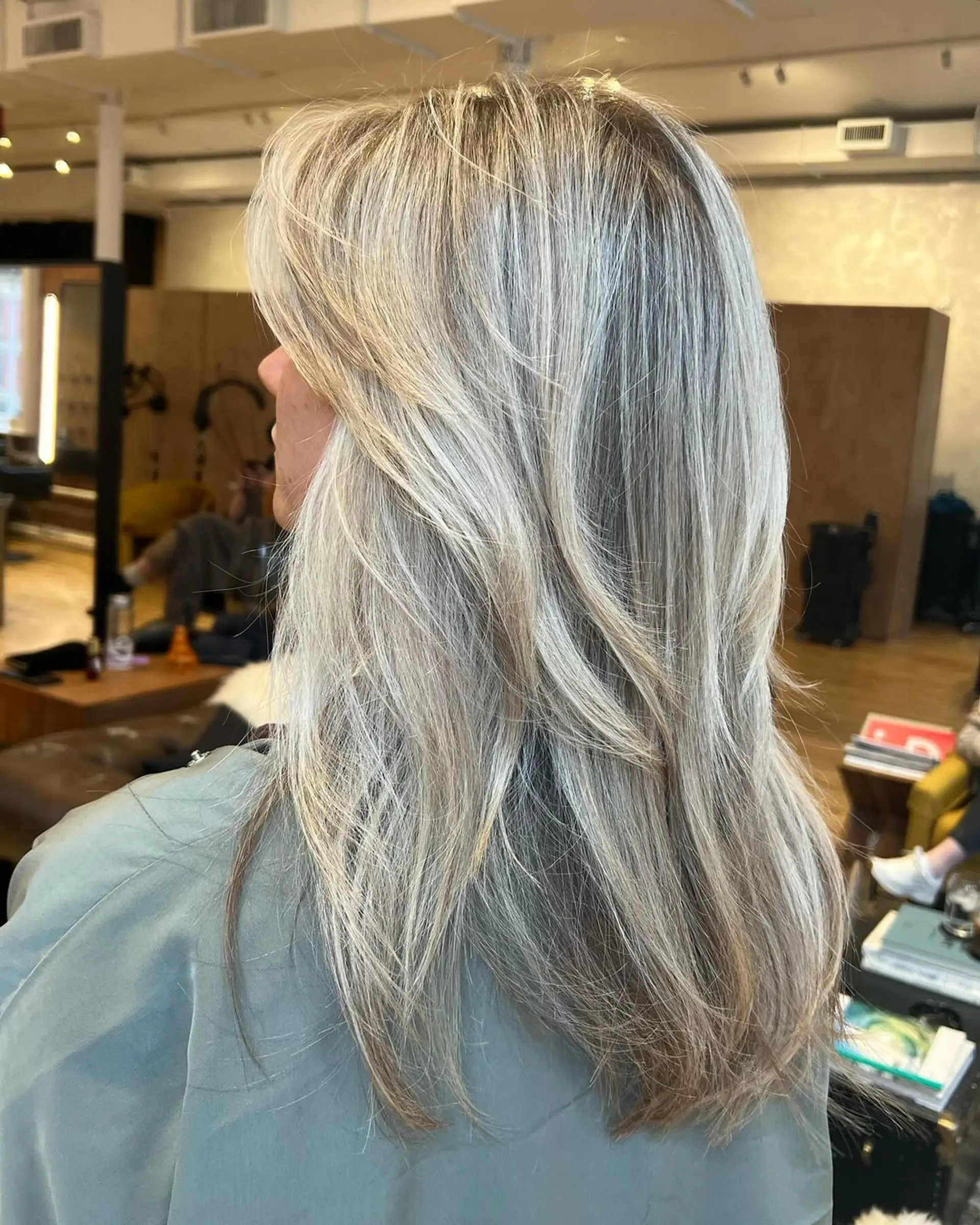 Long, straight hair with sophisticated layers and a blend of blonde and platinum hues, enhanced by subtle highlights and complemented by a middle part. 2