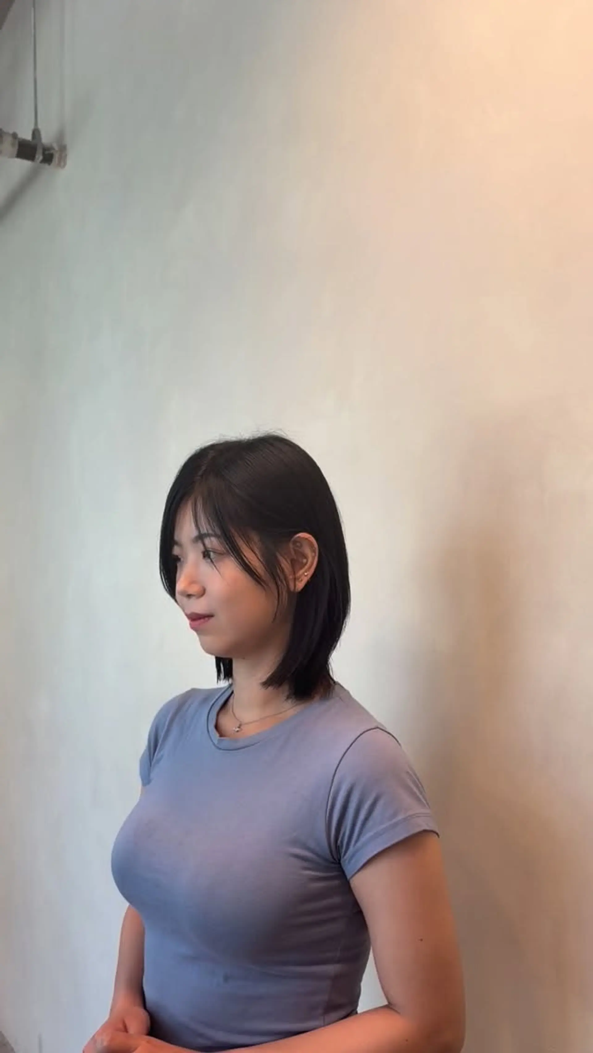 A textured, layered dark bob falling just above the shoulders, styled with soft wispy bangs and subtle face-framing layers tucked behind the ear. 1