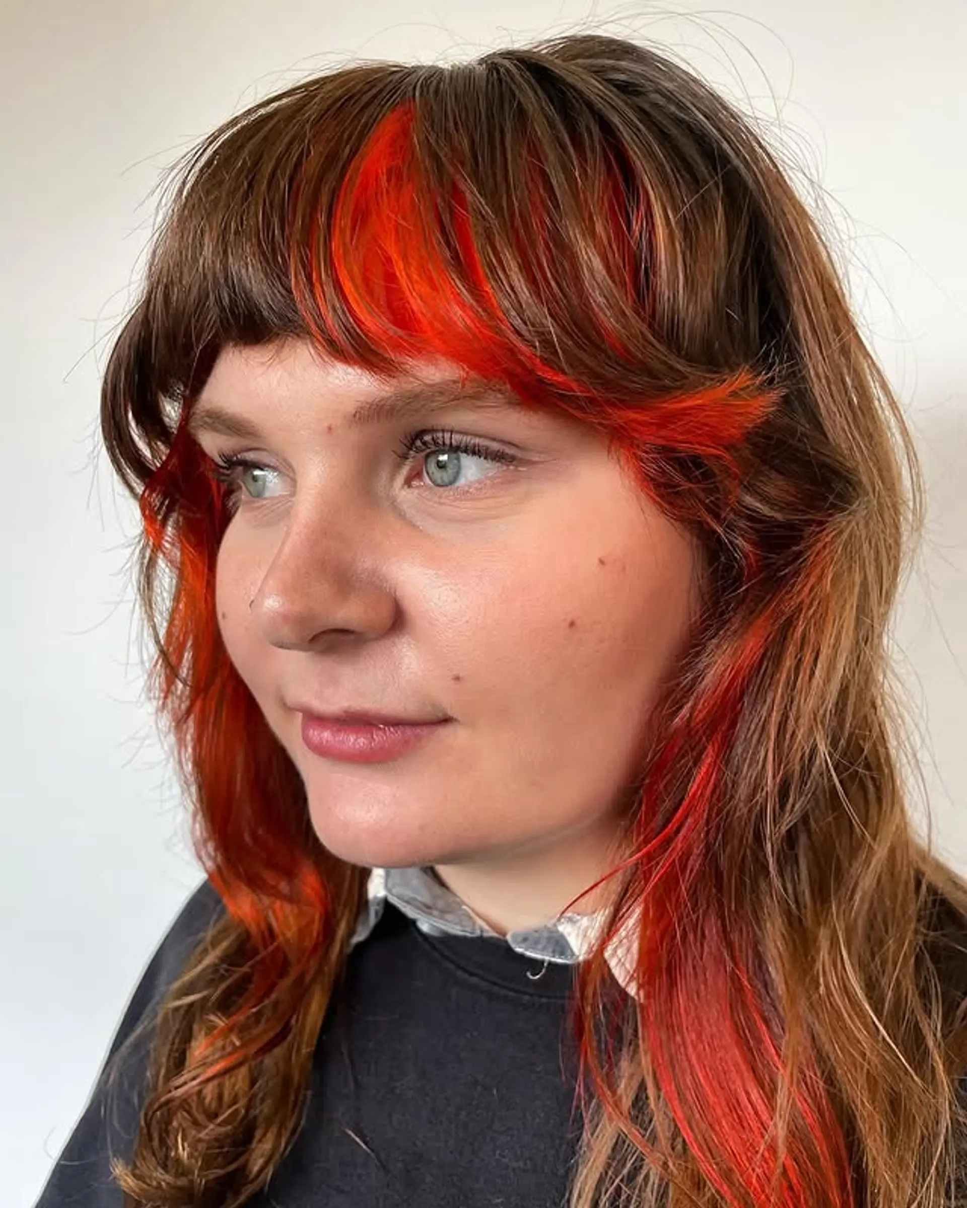 A choppy shag haircut with a full fringe and statement red accents. 1