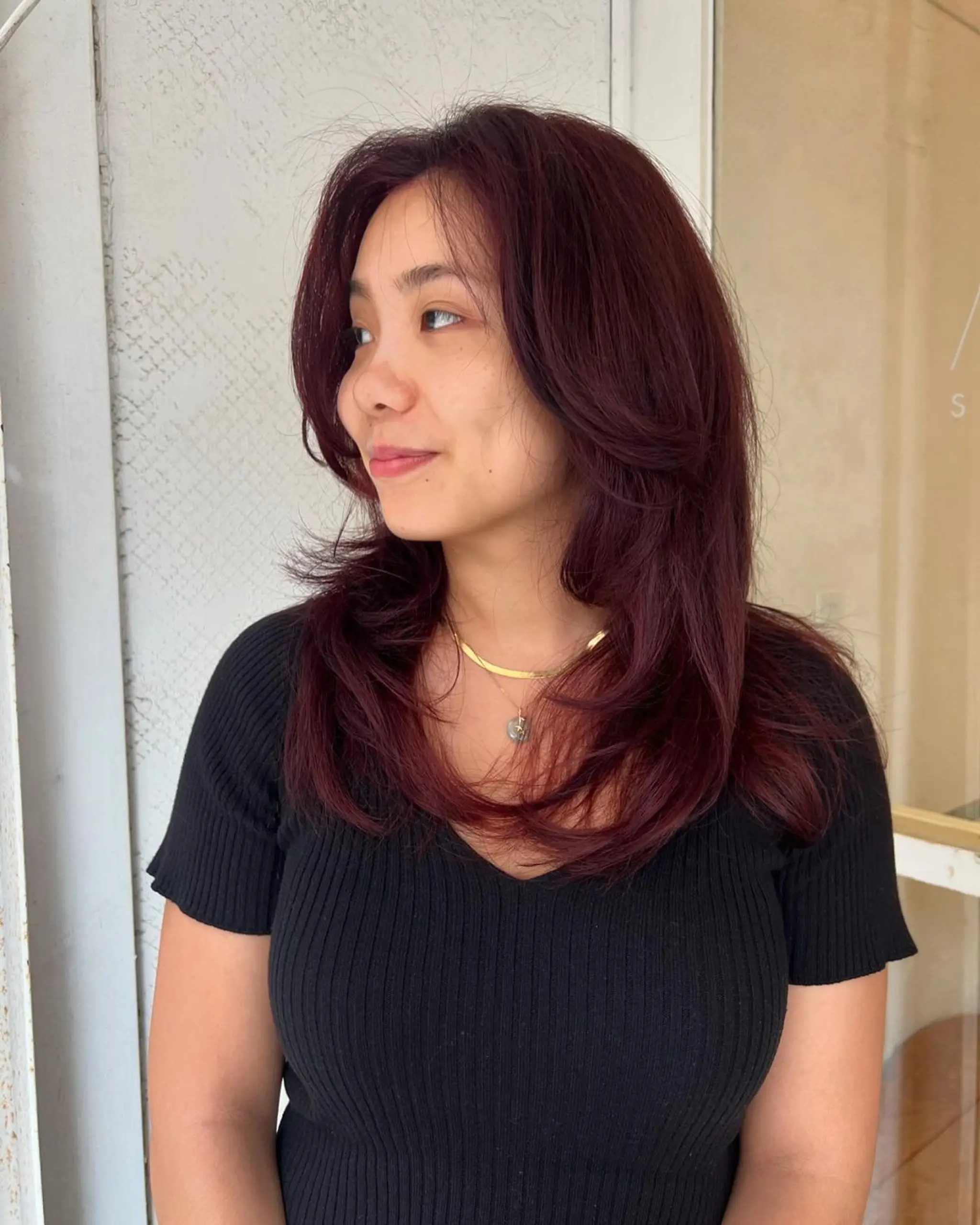 Rich burgundy long hair, wavy and layered with a side part and feathery ends, creating a voluminous and flowing look.