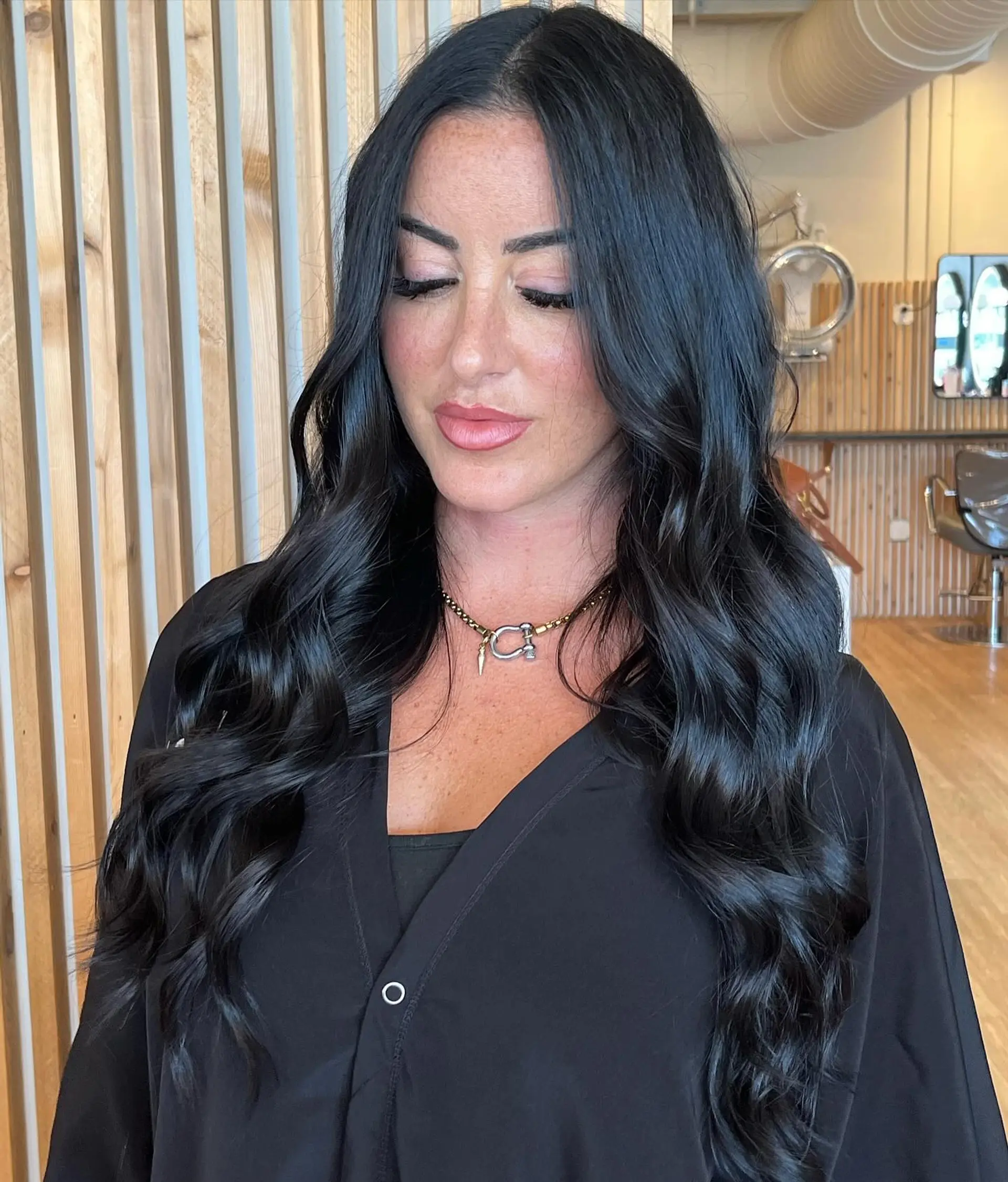 Long, glossy midnight black hair styled with loose, polished waves and a center part. 1
