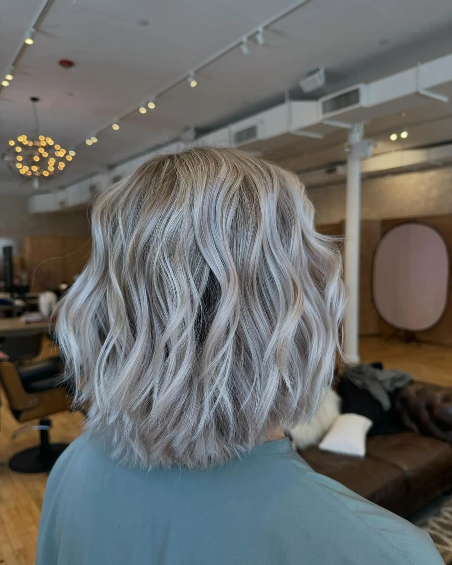 Medium-length wavy cut with a blend of silver and light blonde colors, featuring soft waves for a voluminous and chic look. 1