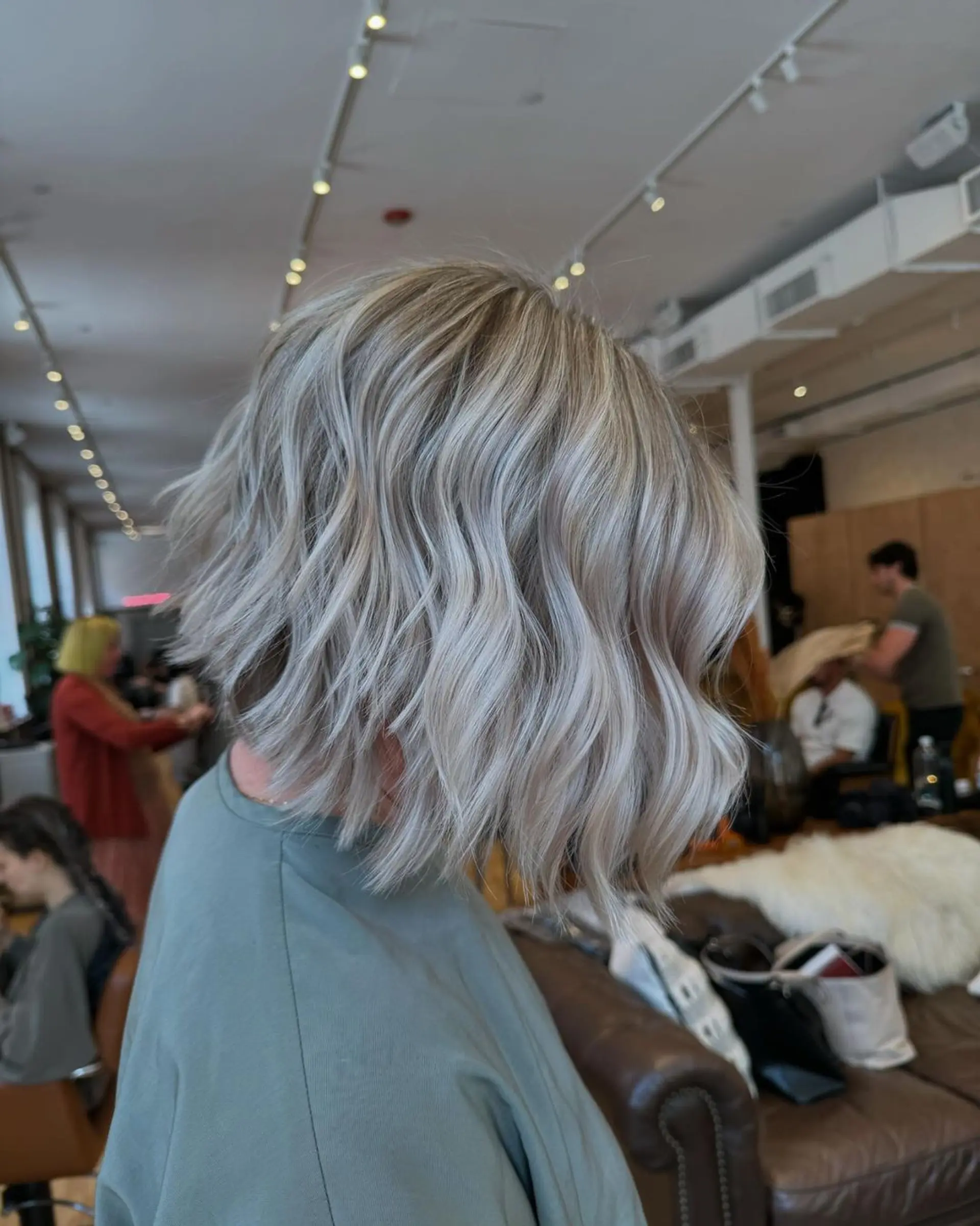 Medium-length wavy cut with a blend of silver and light blonde colors, featuring soft waves for a voluminous and chic look. 2