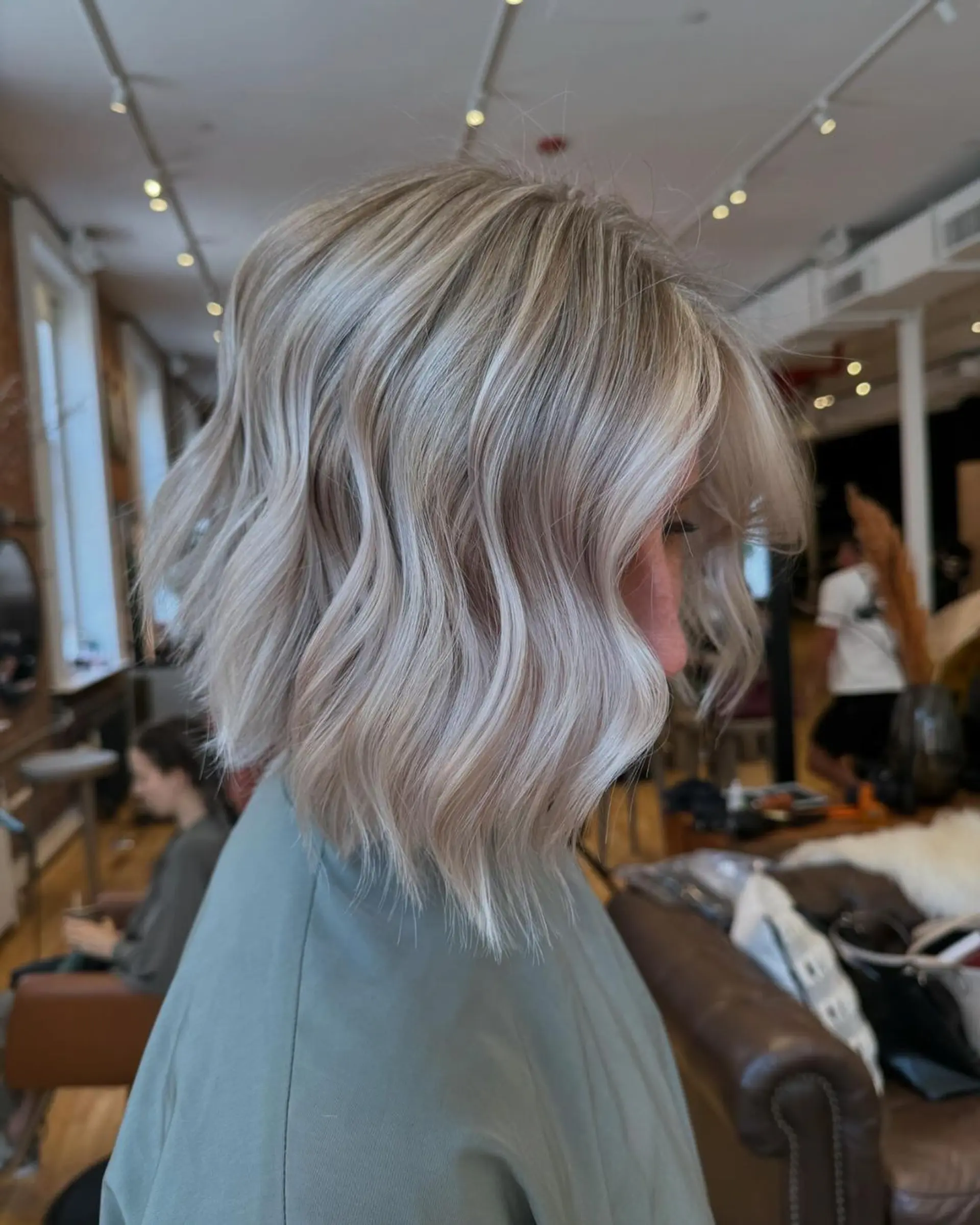 Medium-length wavy cut with a blend of silver and light blonde colors, featuring soft waves for a voluminous and chic look. 3