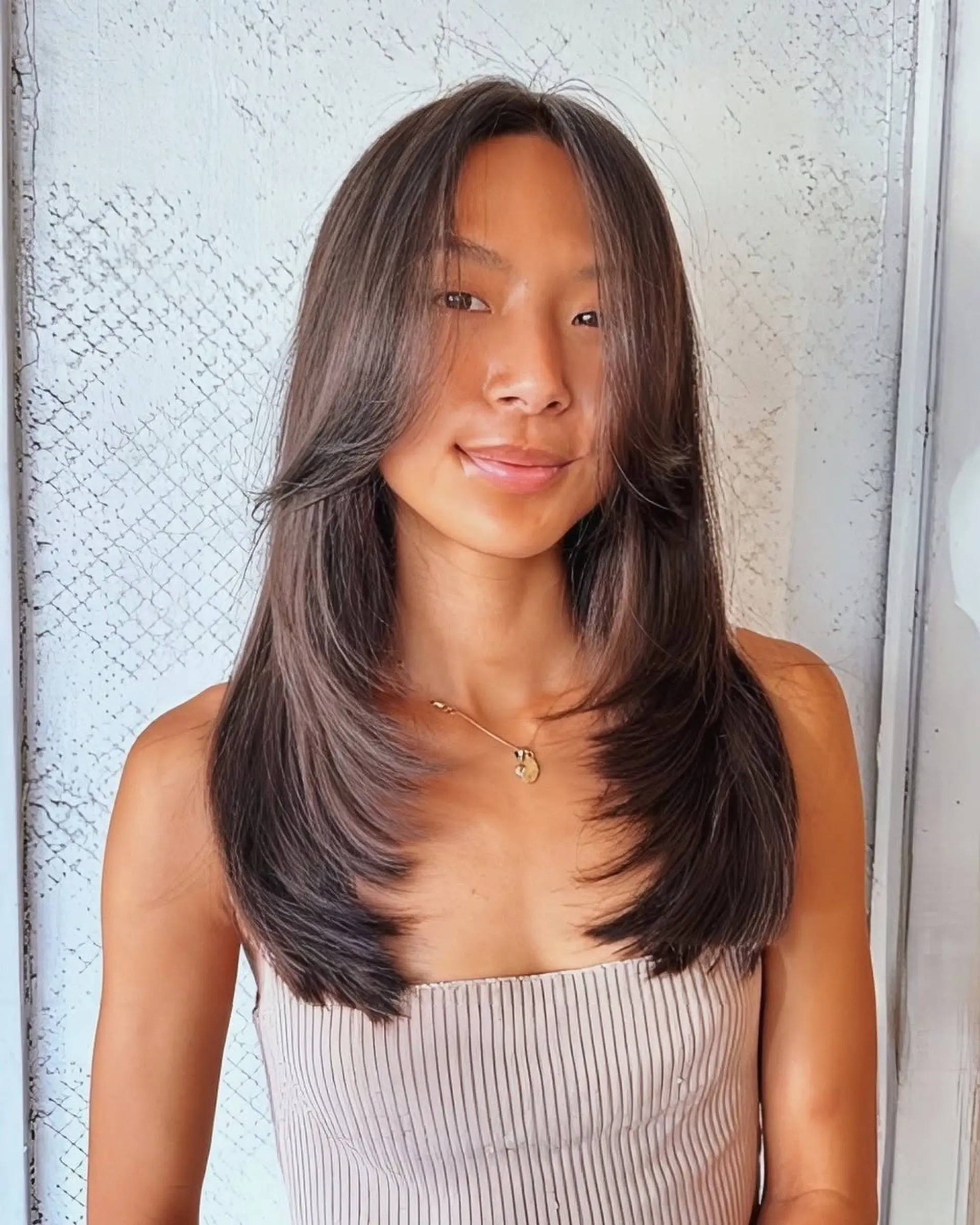 Long, straight, dark brown hair with layered, face-framing strands and feathered ends, offering a natural shine and elegant movement. 1