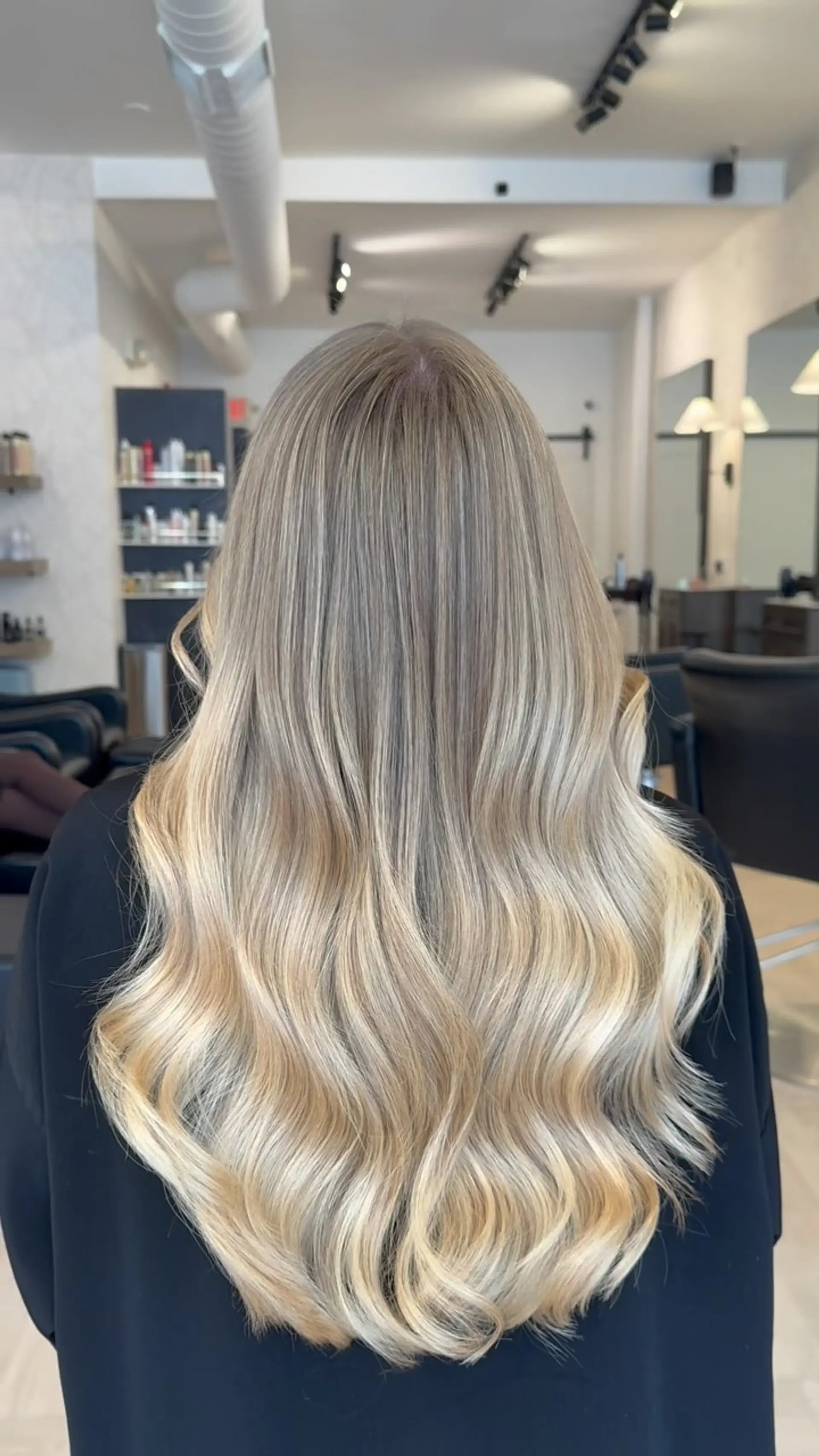Long dimensional blonde hair styled in smooth, voluminous cascading waves. 1