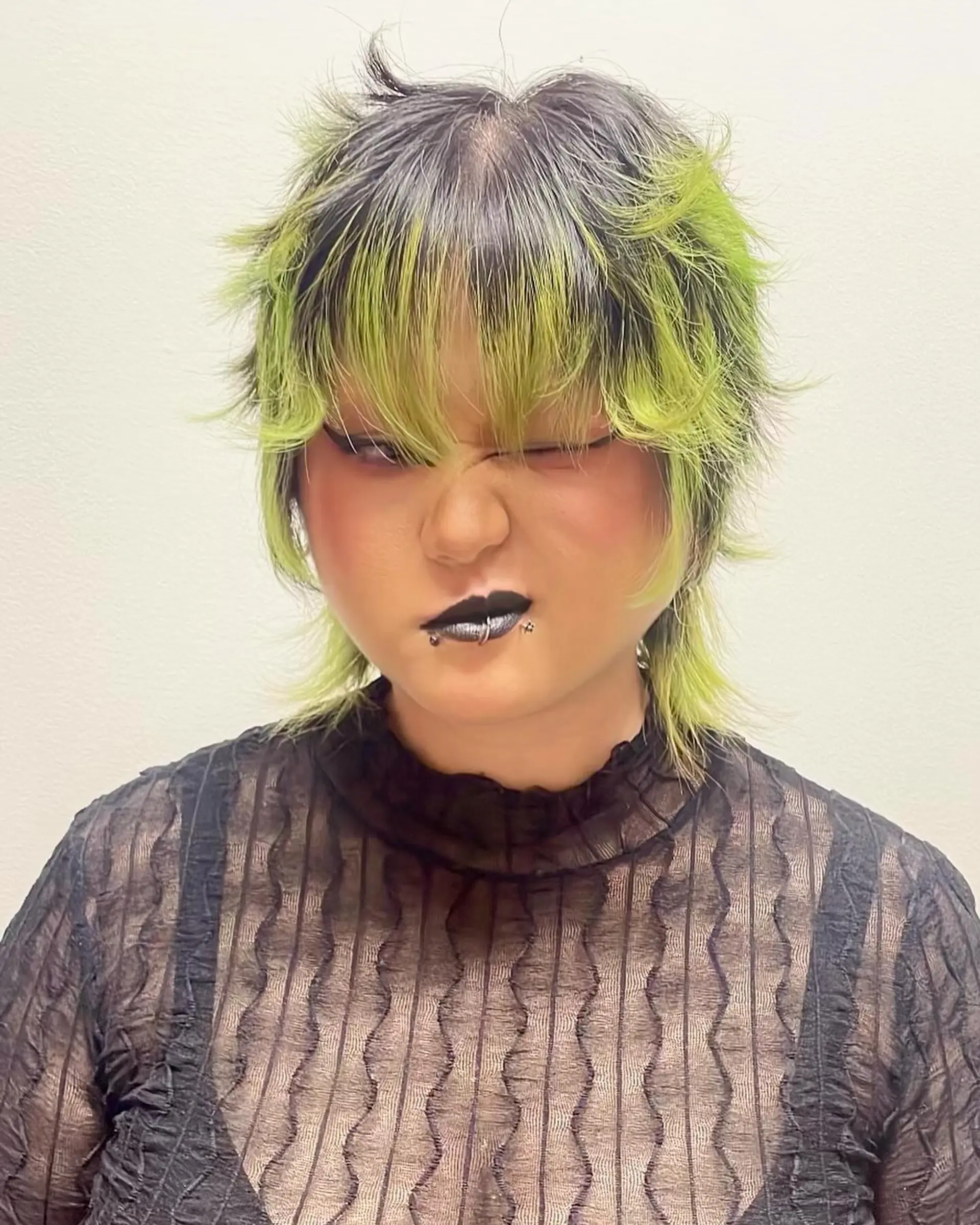 Edgy short hairstyle with choppy layers, neon green and black color contrast, and bold bangs transforming into textured ends for a dynamic look. 1