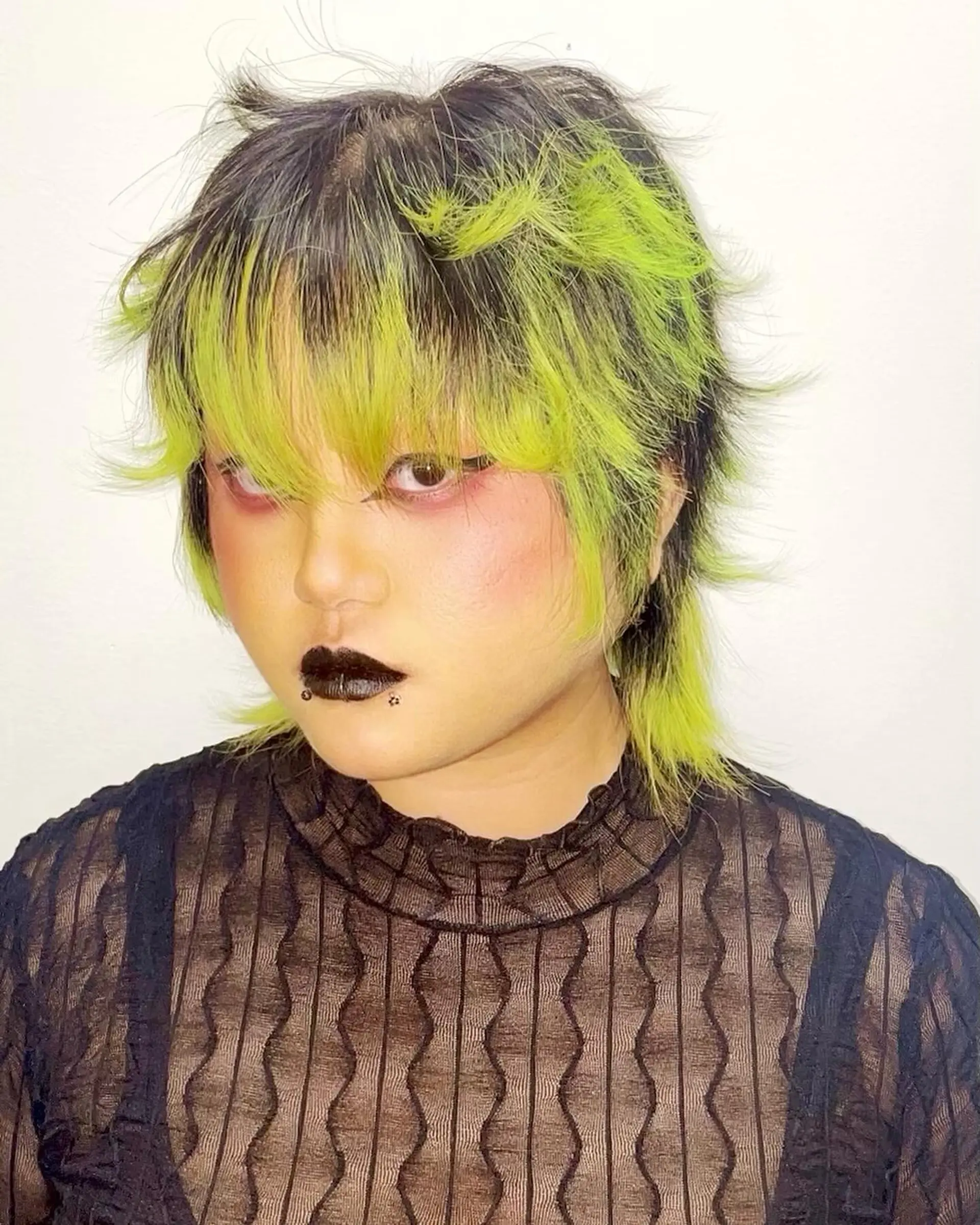 Edgy short hairstyle with choppy layers, neon green and black color contrast, and bold bangs transforming into textured ends for a dynamic look. 2
