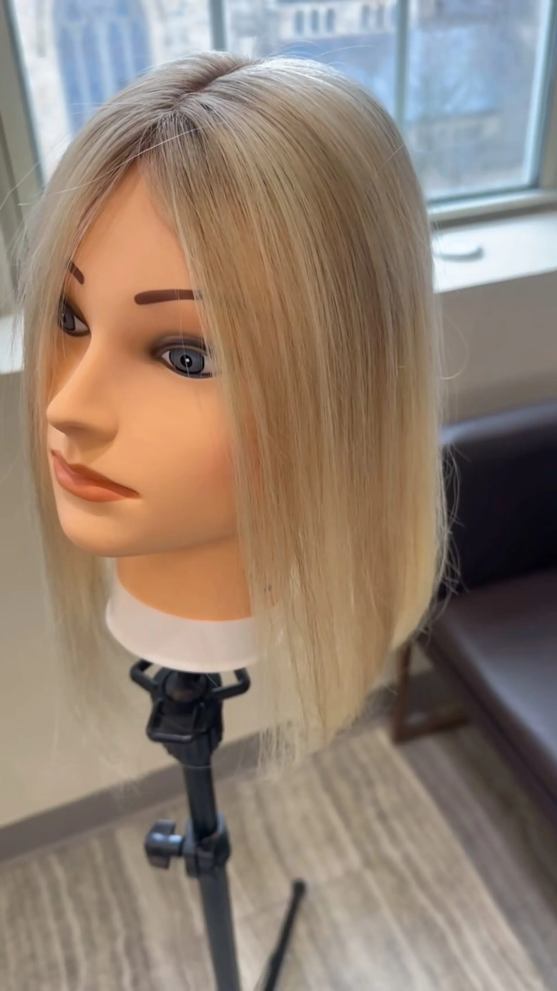 A sleek, straight platinum blonde lob hair topper featuring soft root shading for added depth and dimension. 1