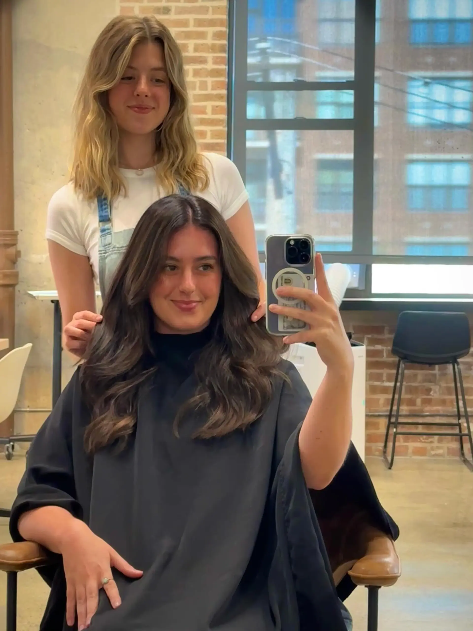A long layered cut featuring prominent face-framing layers that create a soft, voluminous shape around the face. The hair is styled with a center part and soft, bouncy waves, giving it a lively and modern appeal. 1