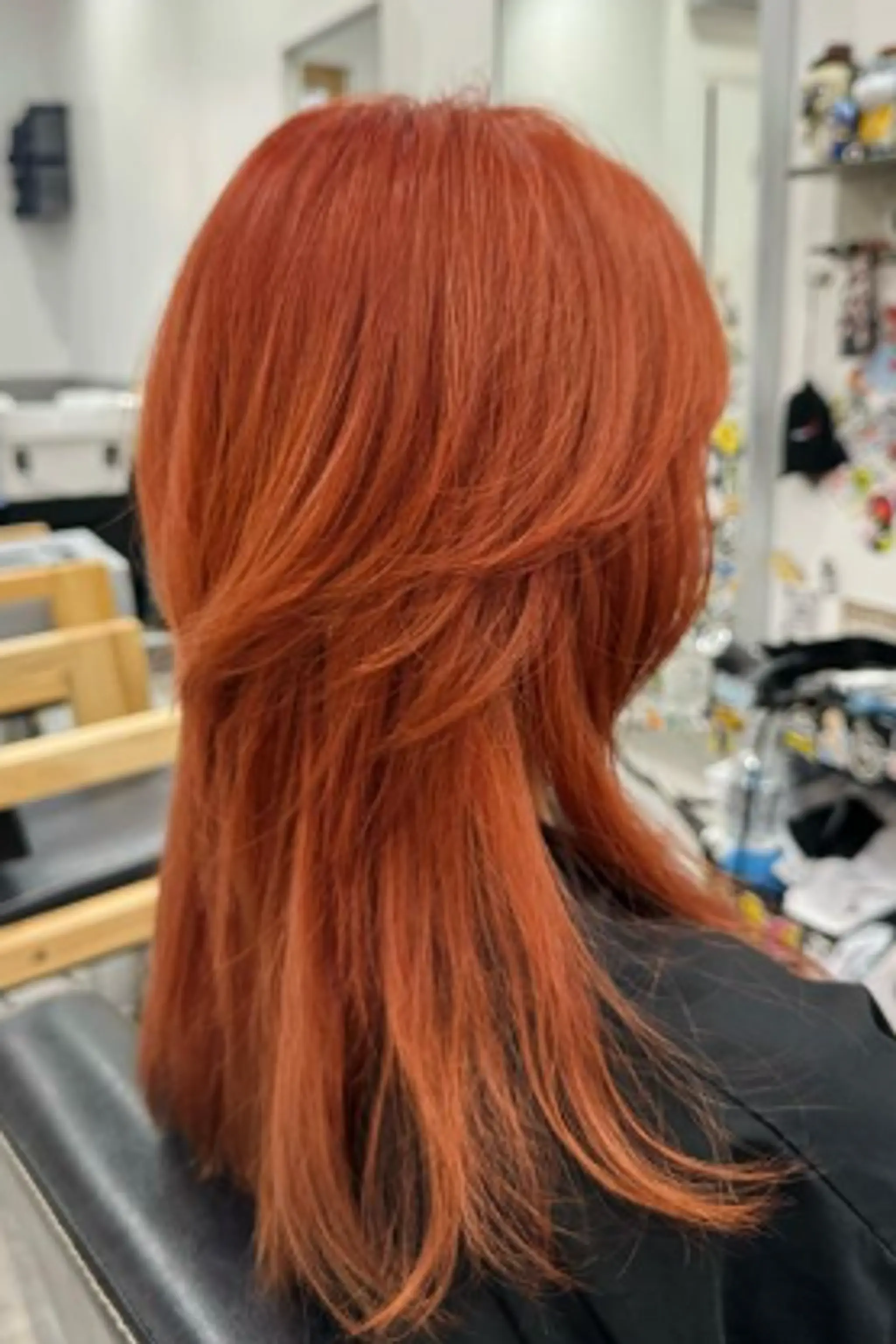 A vibrant, medium-length hairstyle with straight texture. The hair features fiery red and copper hues, layered cuts with a feathery texture, and blunt ends, offering movement and volume.
