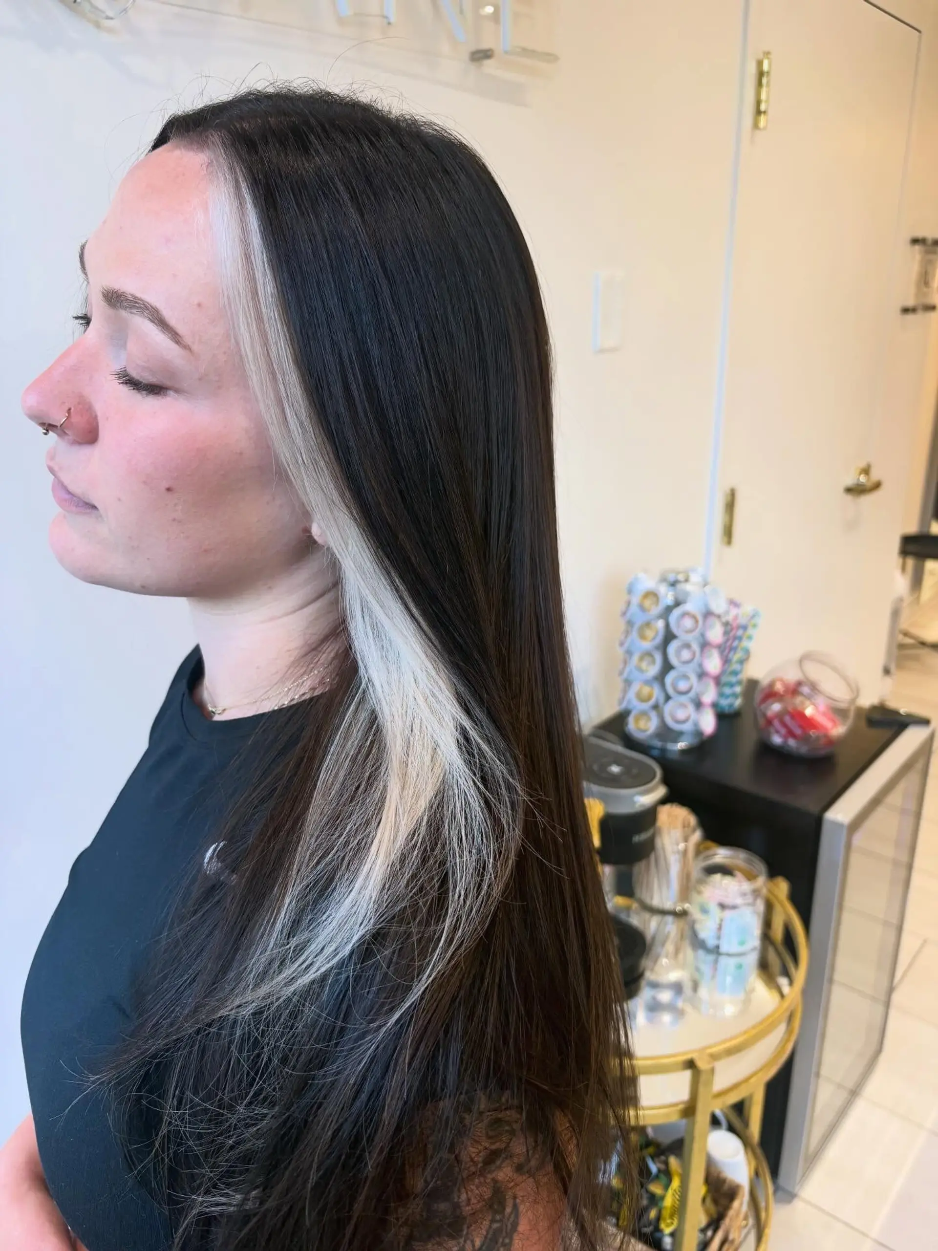 Straight, long dark brown hair styled with a high-contrast platinum blonde peekaboo face-framing streak. 1