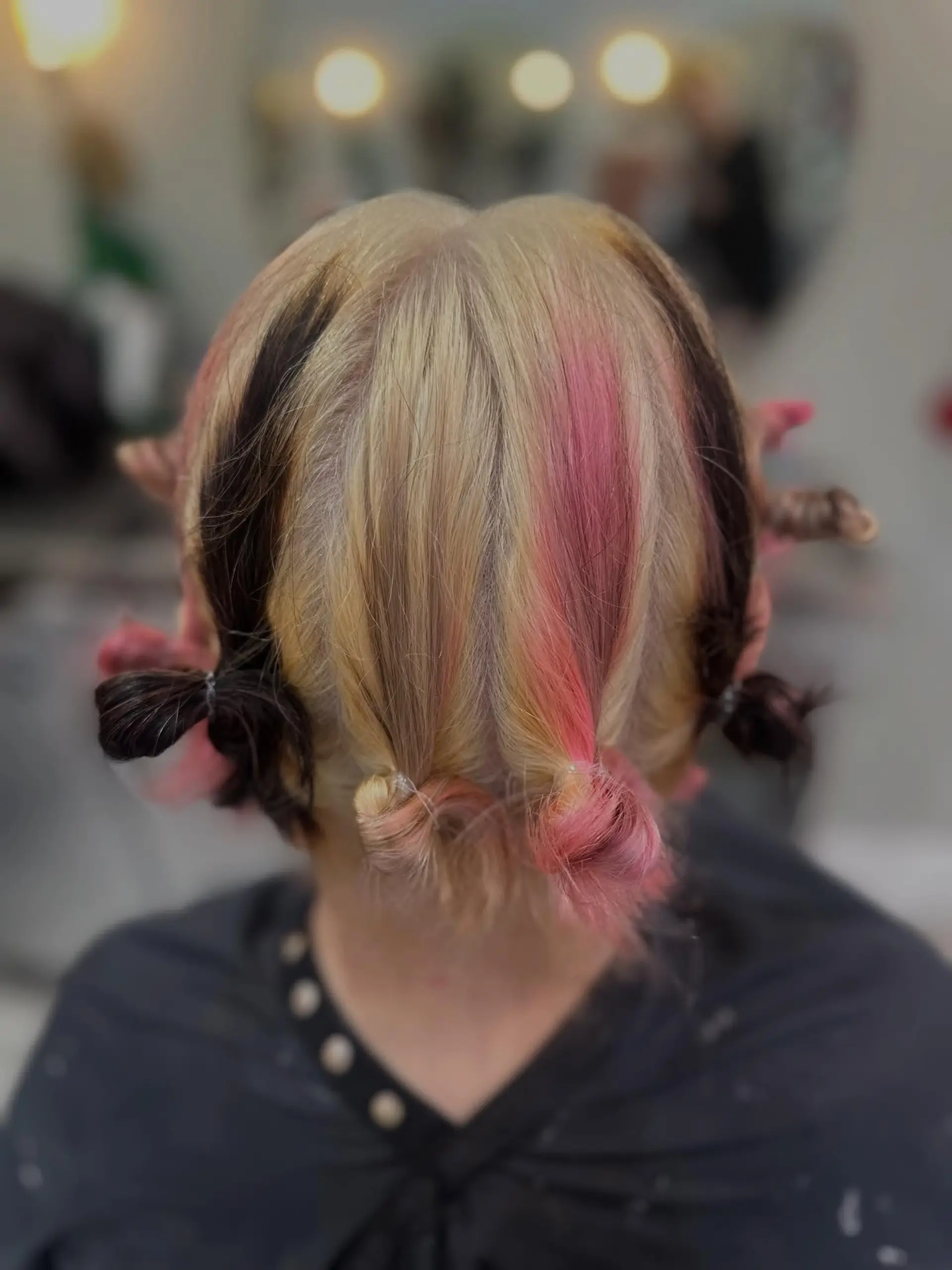 A creative Neapolitan-inspired color placement featuring sections of platinum blonde, pastel pink, and rich chocolate brown, gathered into small parted buns to highlight each tone. 1