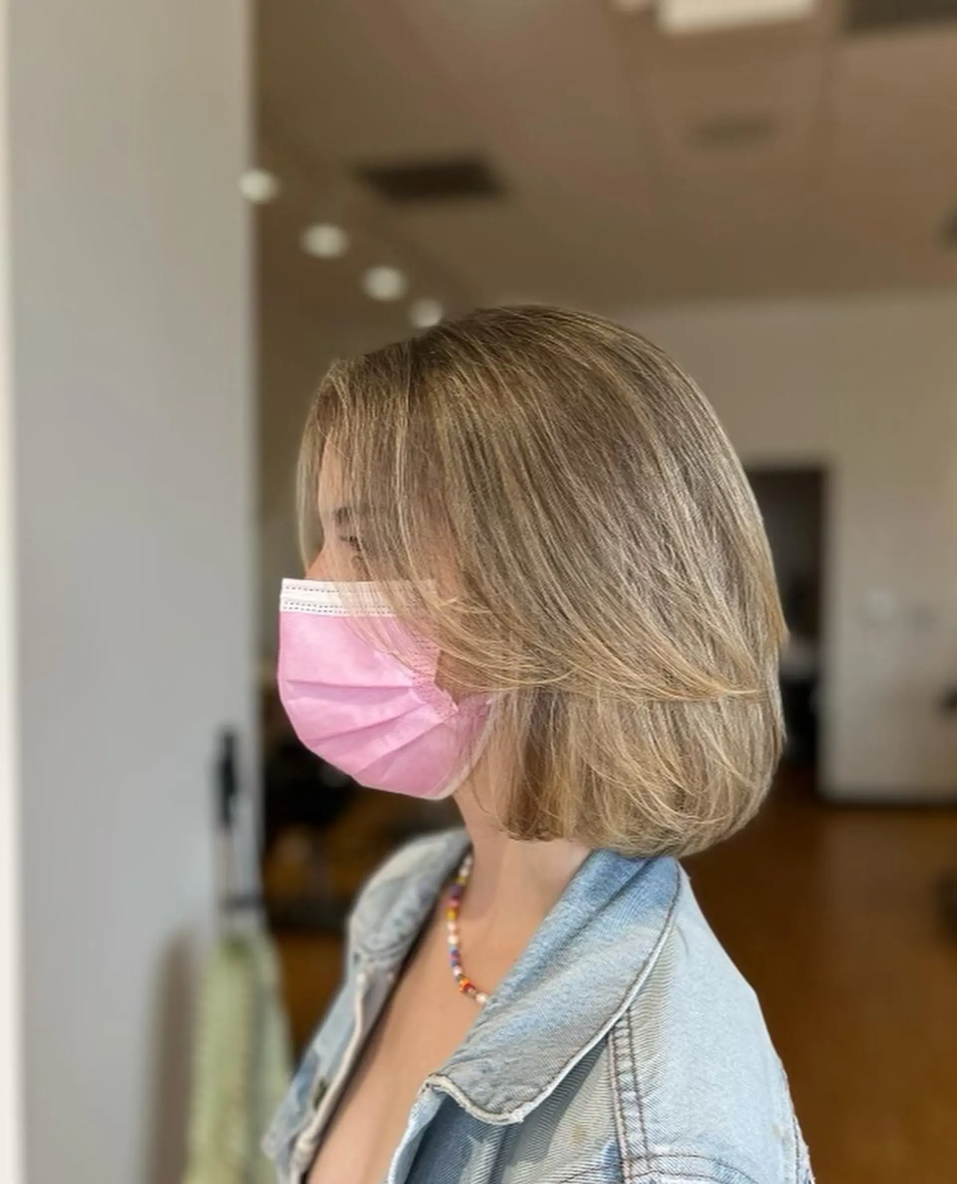 A dimensional layered bob haircut featuring soft face-framing layers and blended ash blonde highlights styled with a rounded blowout. 1