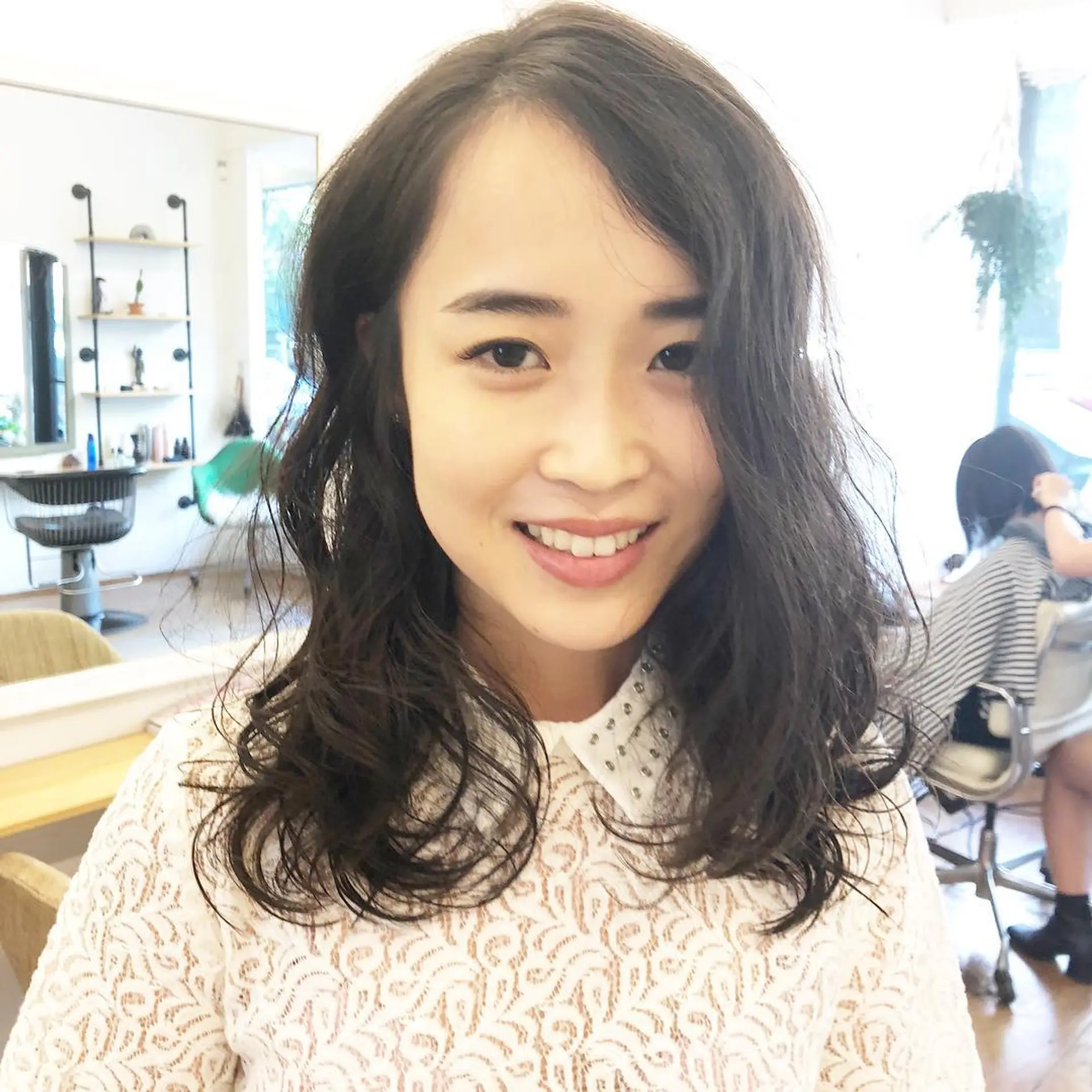 This hairstyle features medium-length, wavy hair with a natural shine that frames the face beautifully. The waves are lightly tousled, giving an effortless and casual look. The hair falls just past the shoulders, side-parted to add a touch of asymmetry and dynamism. 1