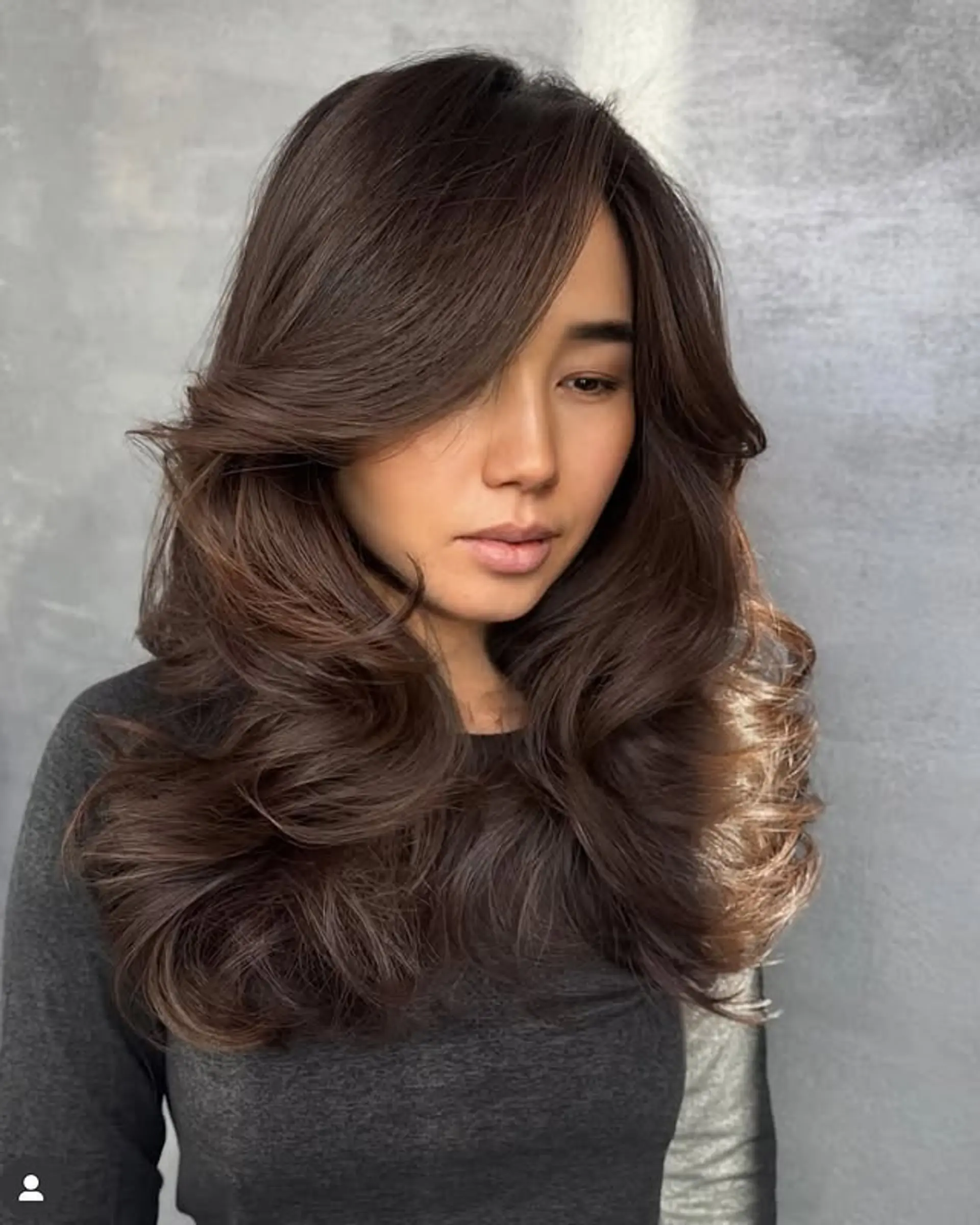 This hairstyle features long, wavy hair with voluminous layers and a center part. 1