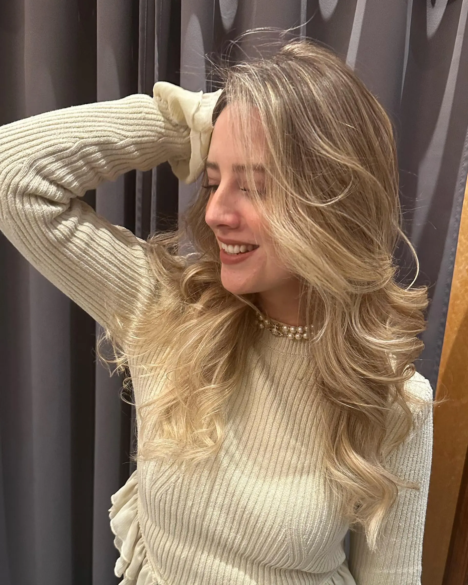 Long layered blonde hair styled into a voluminous, bouncy blowout with soft flowing curls. 1