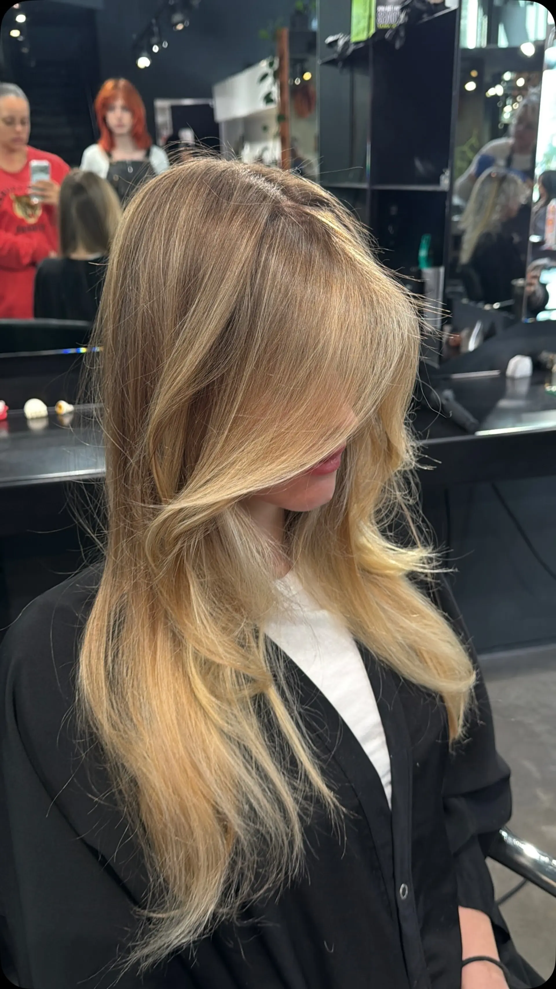 Long, dimensional golden blonde hair featuring seamless balayage highlights, face-framing curtain layers, and a soft blown-out finish. 1