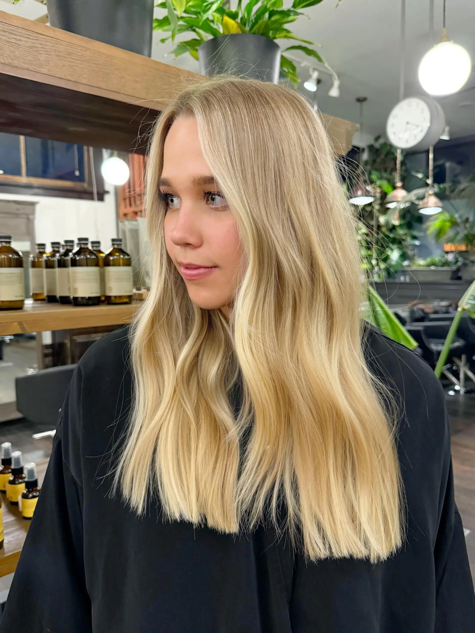 Long buttery blonde hair cut with clean ends and styled with subtle, effortless mid-length waves. 1