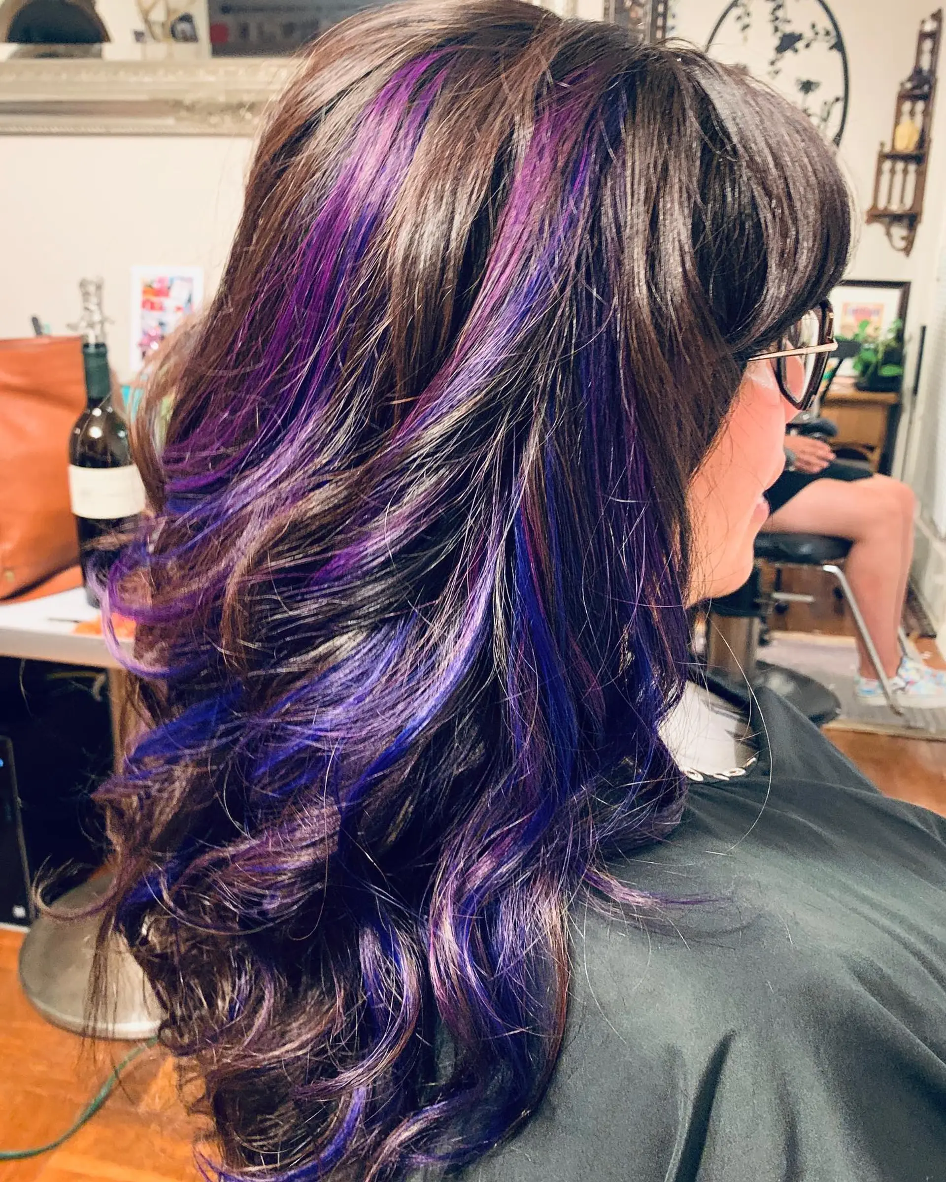 Dark brown layered hair styled with loose curls and accented with vibrant purple and violet tape-in highlights. 1