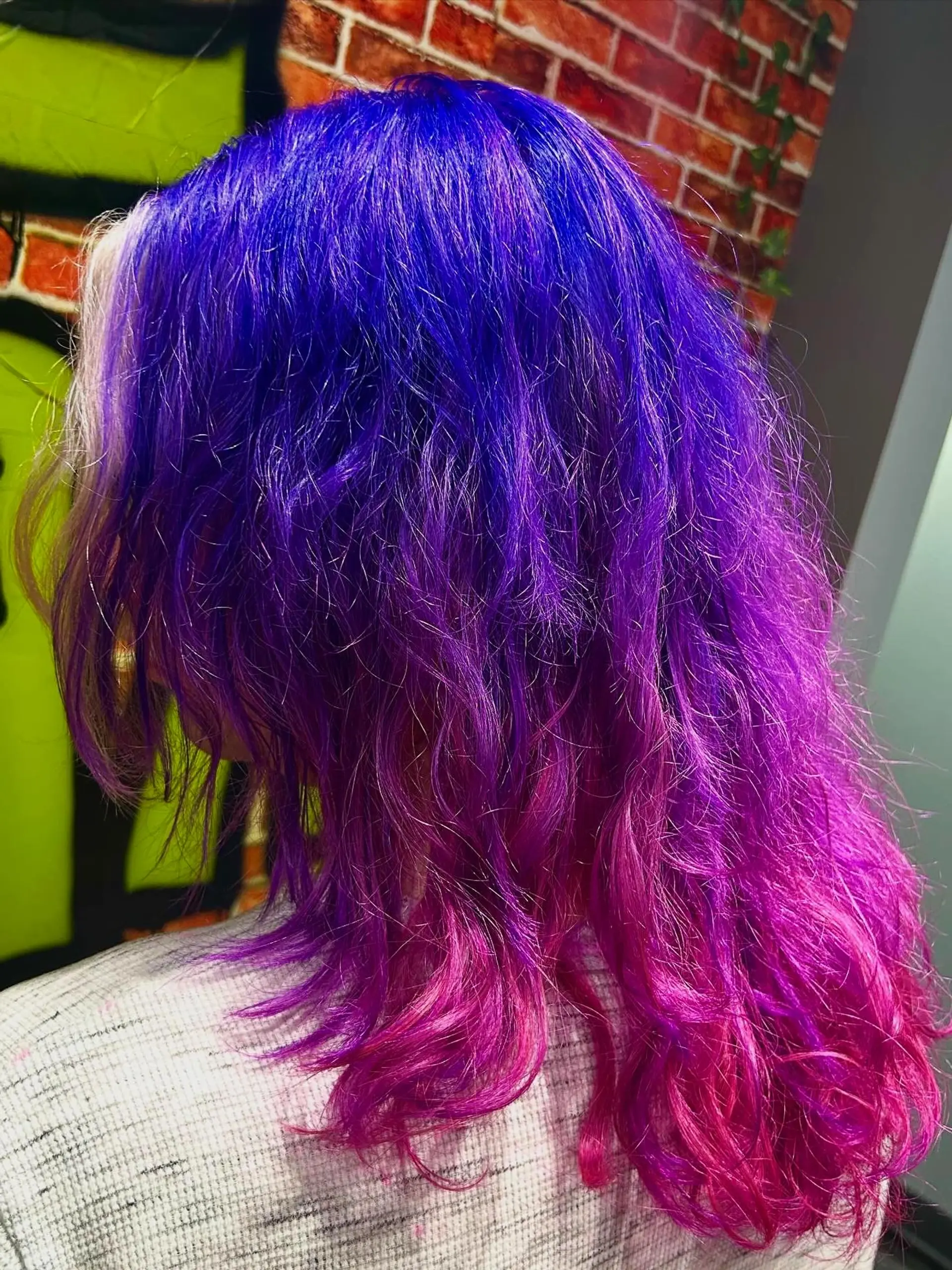 Vibrant medium-length wavy hair featuring a deep violet-purple melt blending into brilliant magenta and fuchsia pink at the ends. 1