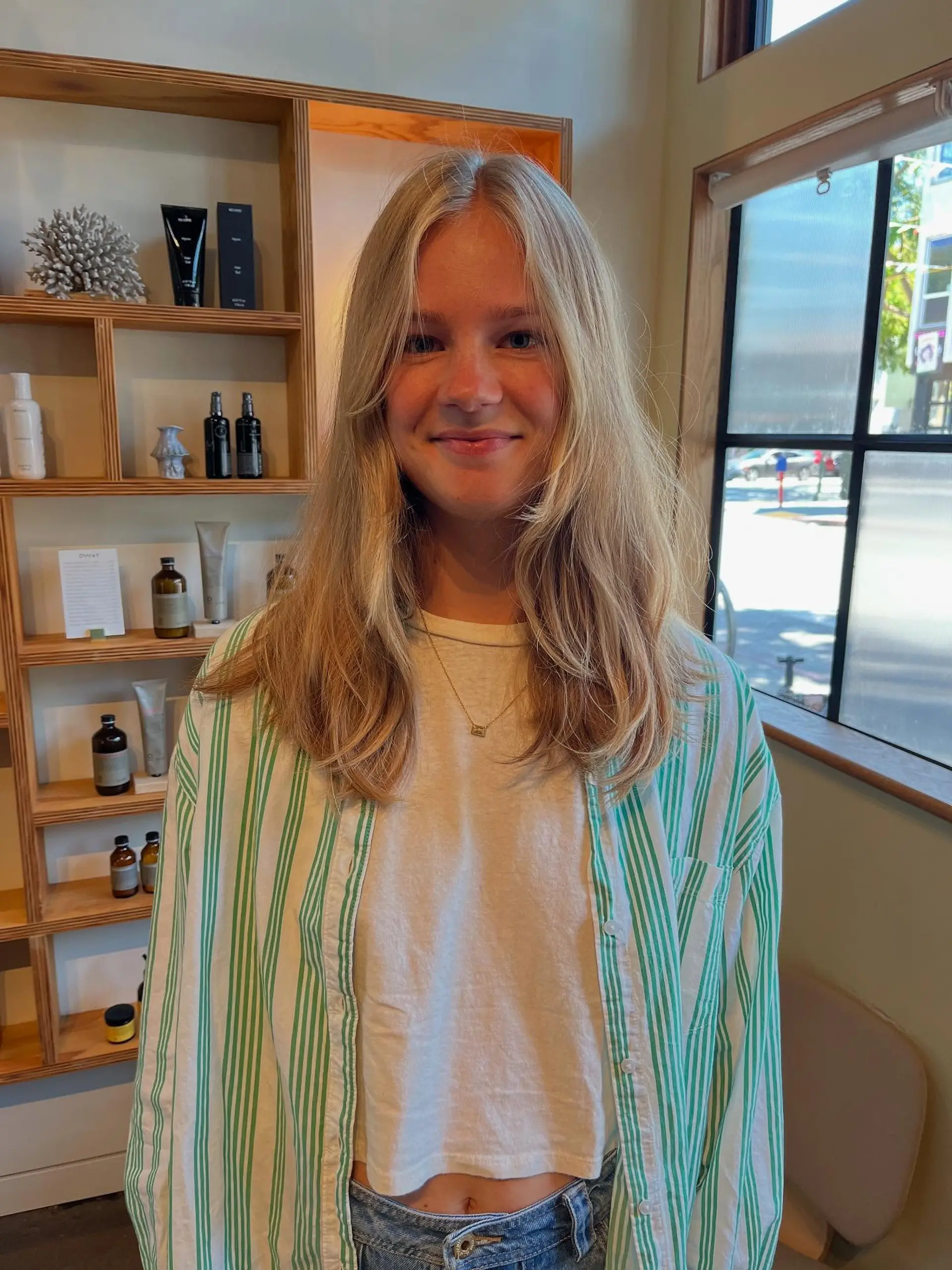 Long blonde hair styled with a center part and face-framing curtain bangs. 1